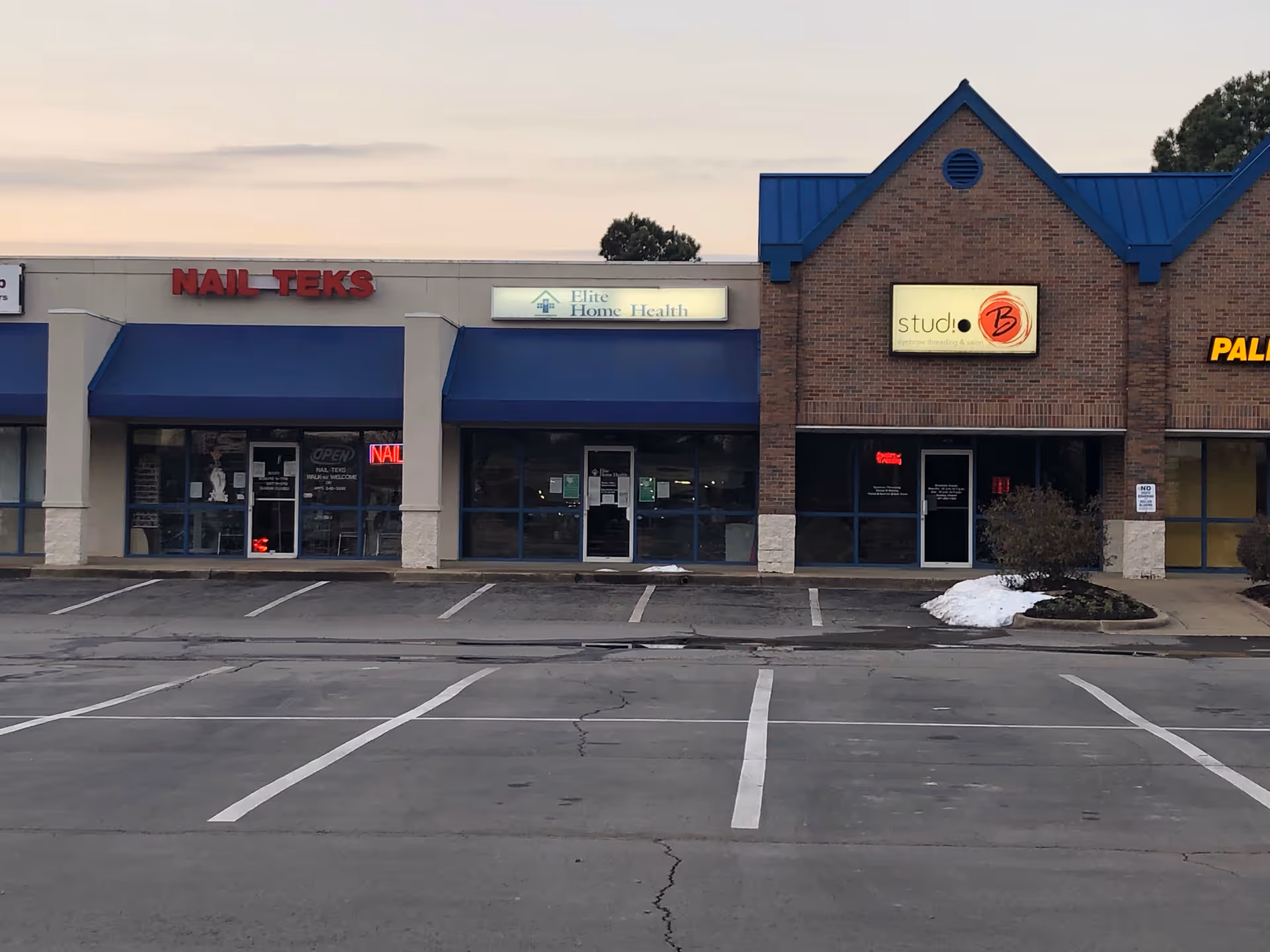 Exterior storefronts of a strip mall with Elite Home Health of Conway signage.