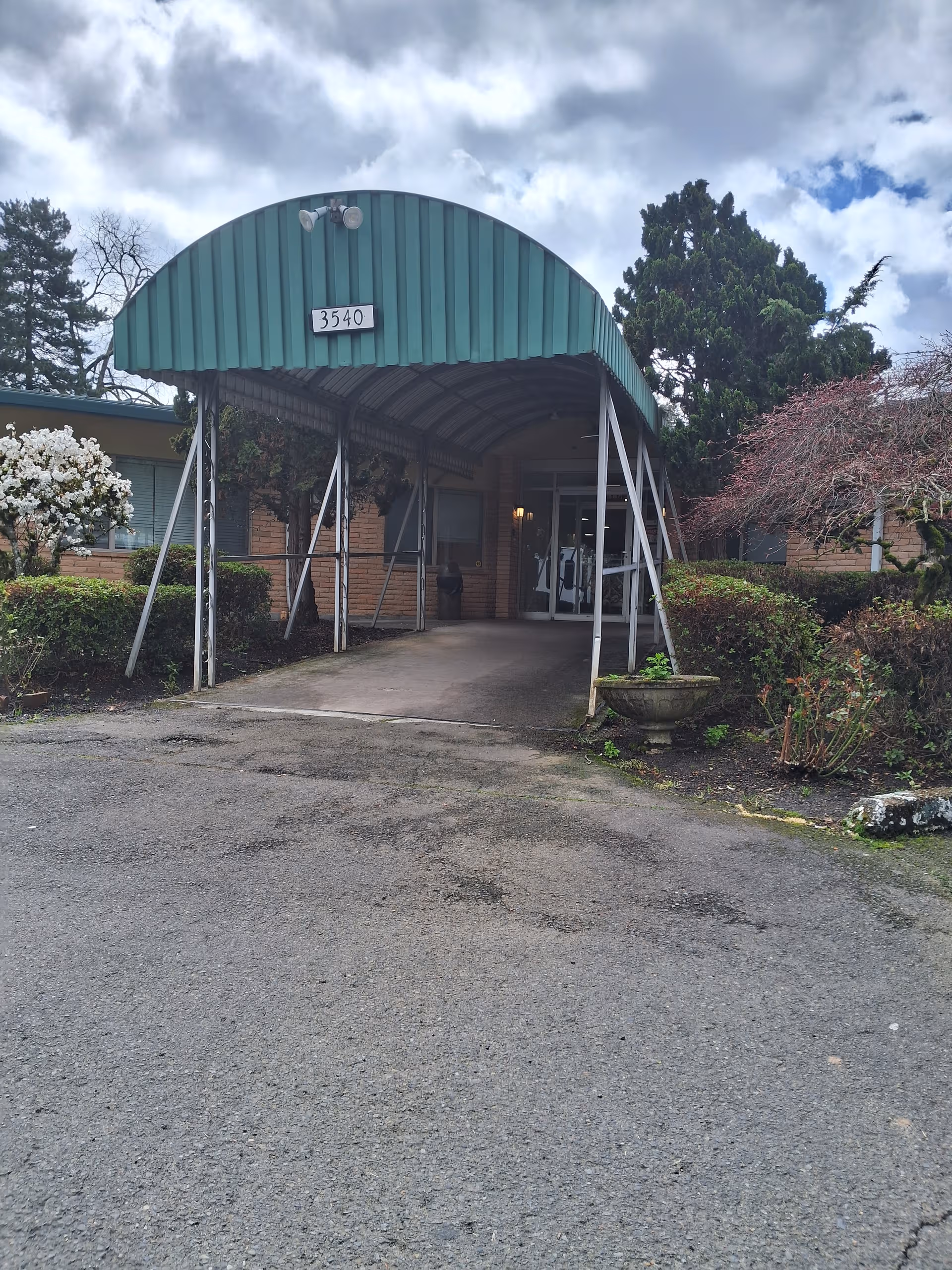 Front entrance of Reedwood Post Acute facility with green curved canopy and landscaping.