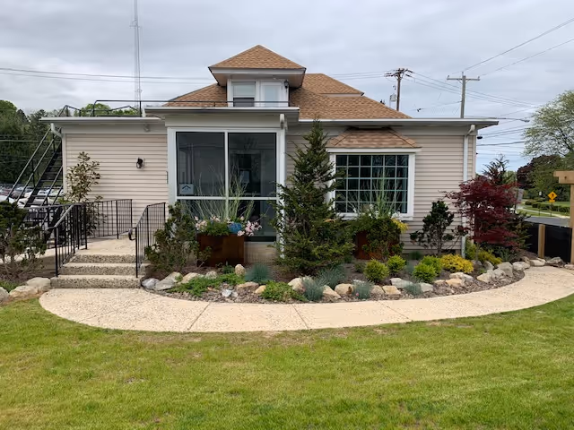 A small single-story building with a landscaped front yard and curved gravel walkway.