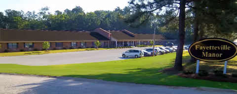 Exterior view of Fayetteville Manor with a parking lot and front sign.