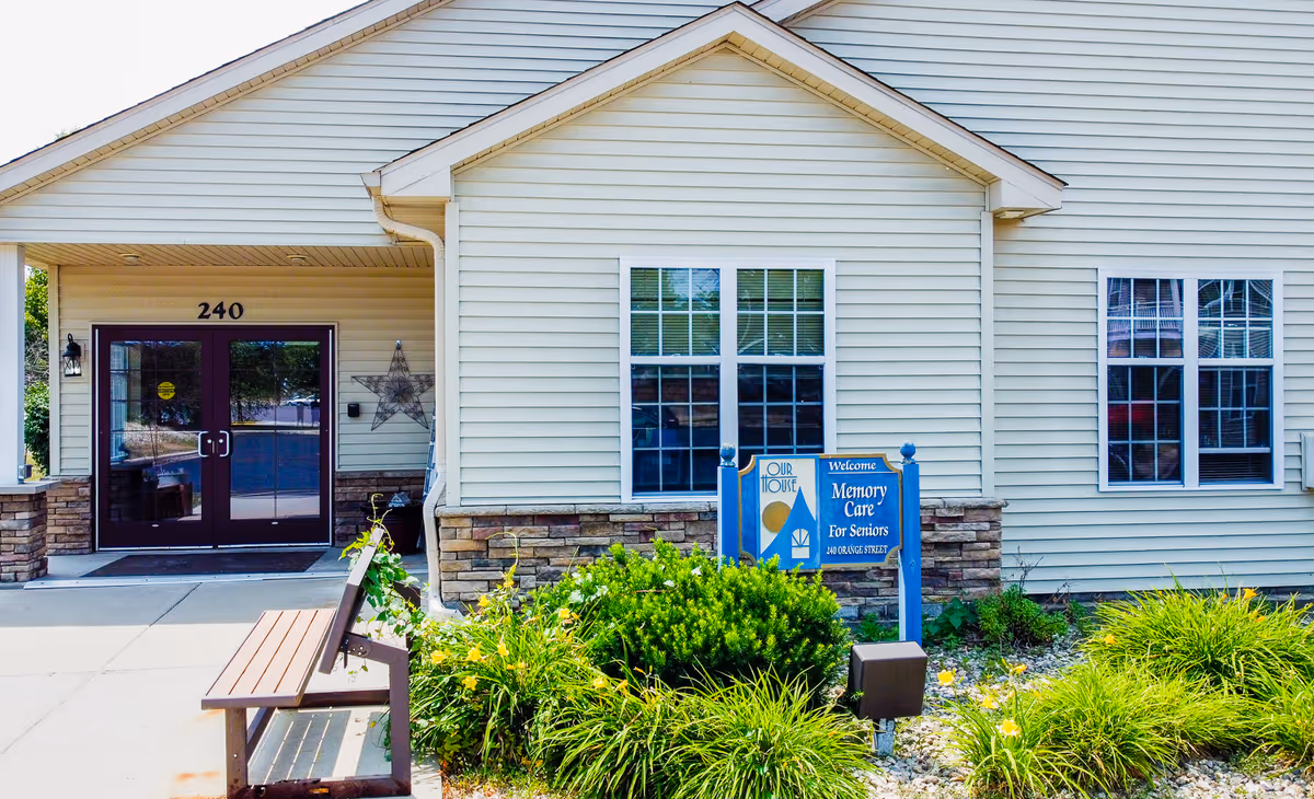 Front exterior of Our House Senior Living with entrance doors and landscaping.