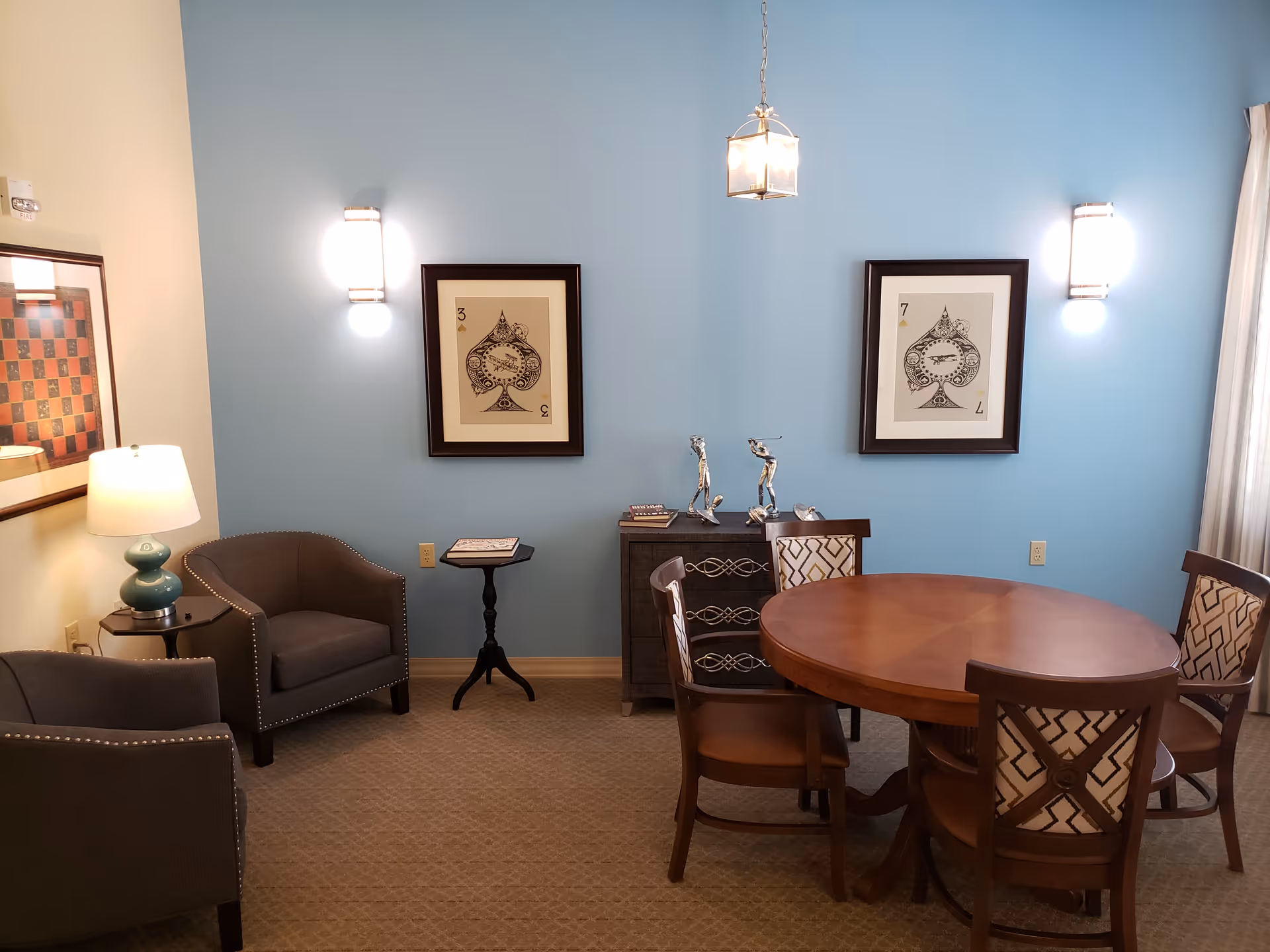 Blue-walled dining area with a round table, chairs, and wall art.