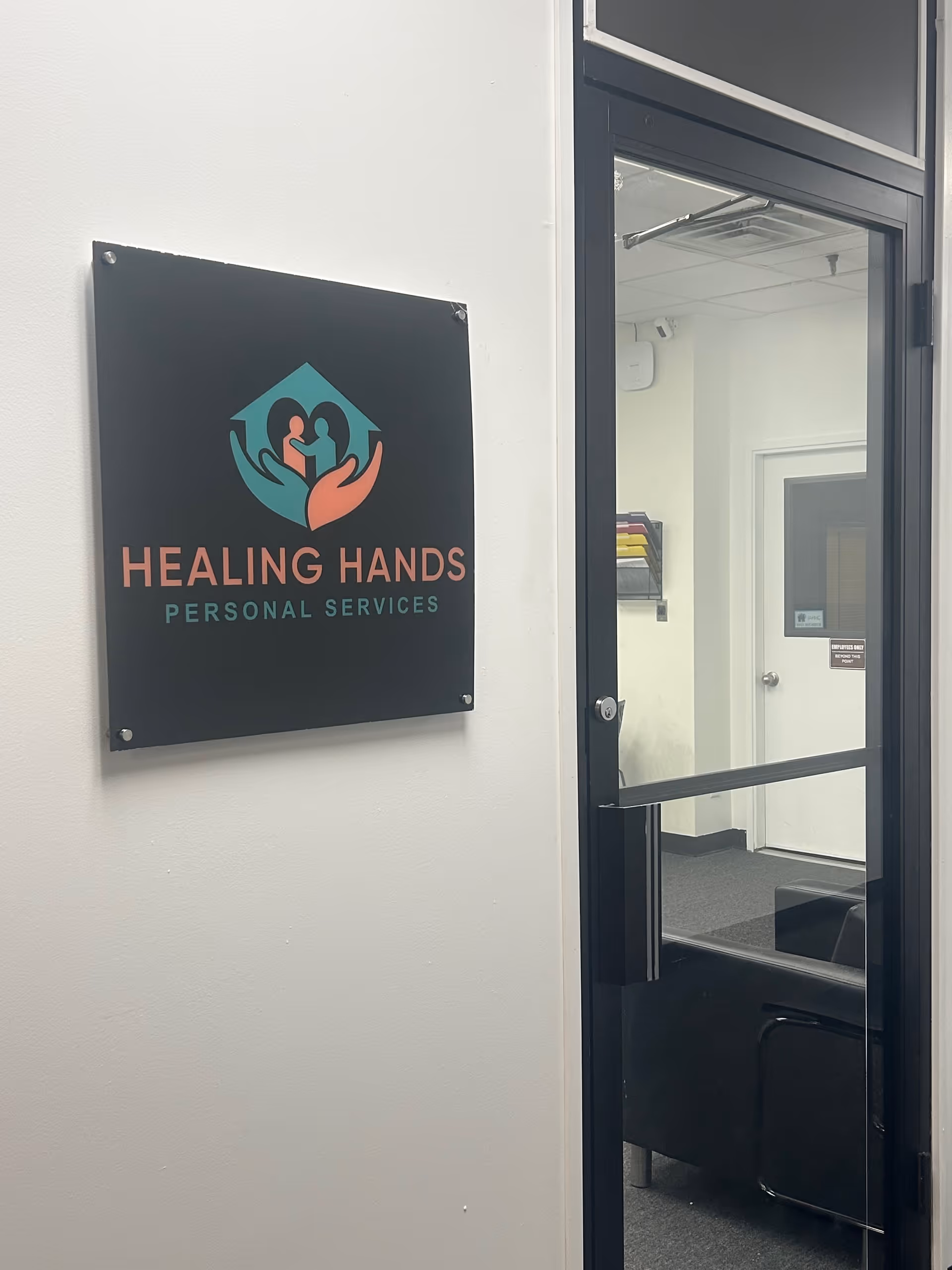 Sign reading Healing Hands Personal Services on wall beside glass entry door into interior.