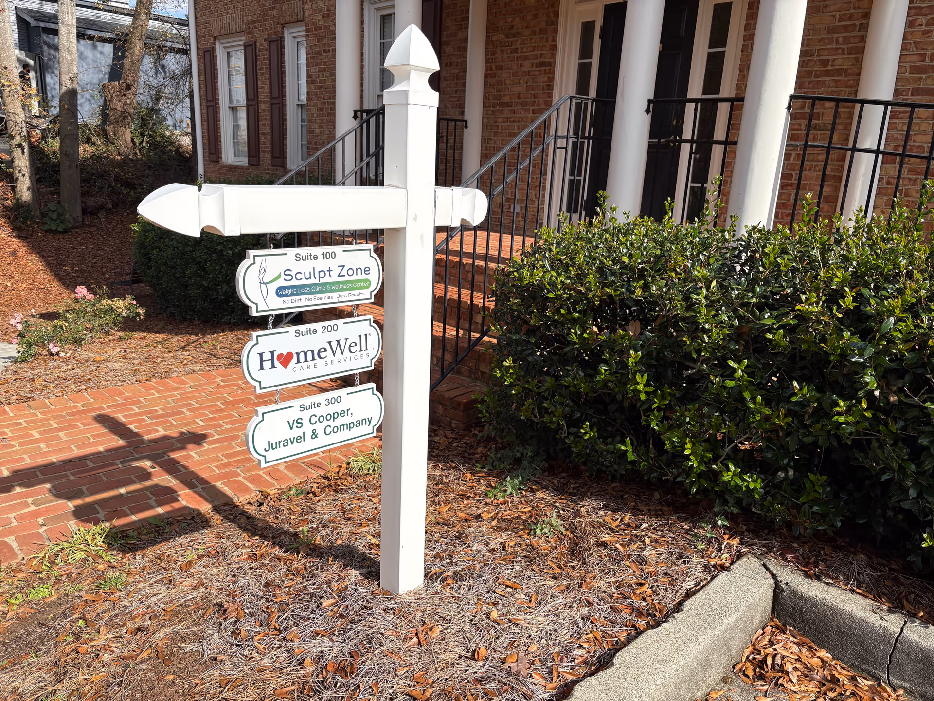Exterior view of a brick facility with a white signpost listing HomeWell Care Services.