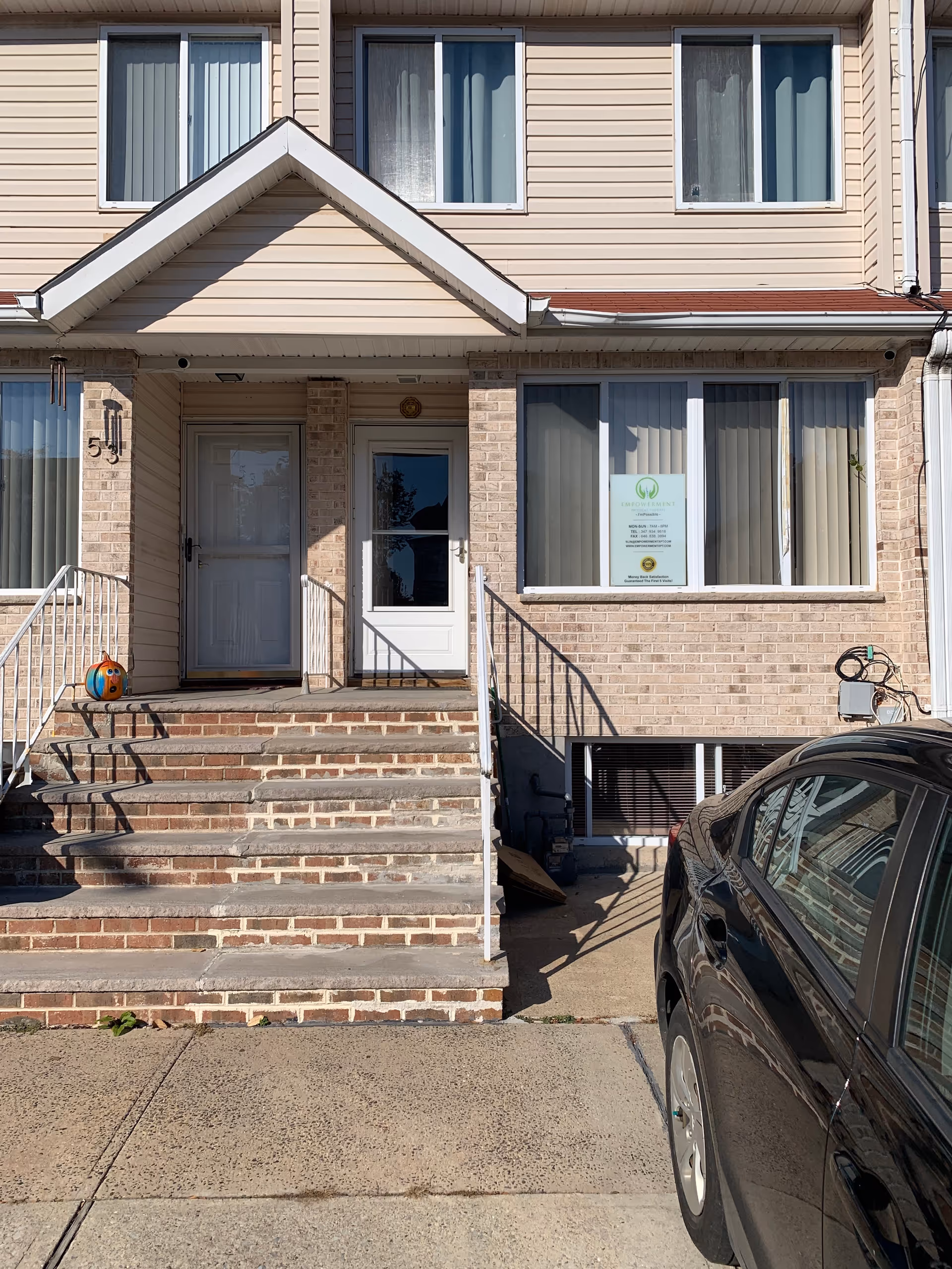 Front entrance of a brick building with steps and a parked car outside.