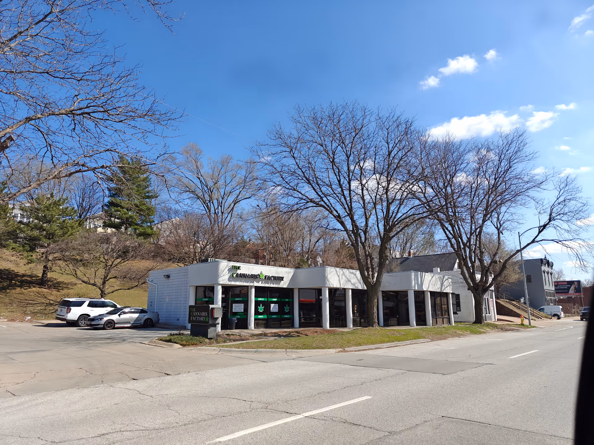 A single-story storefront labeled The Cannabis Factory along a street with leafless trees.