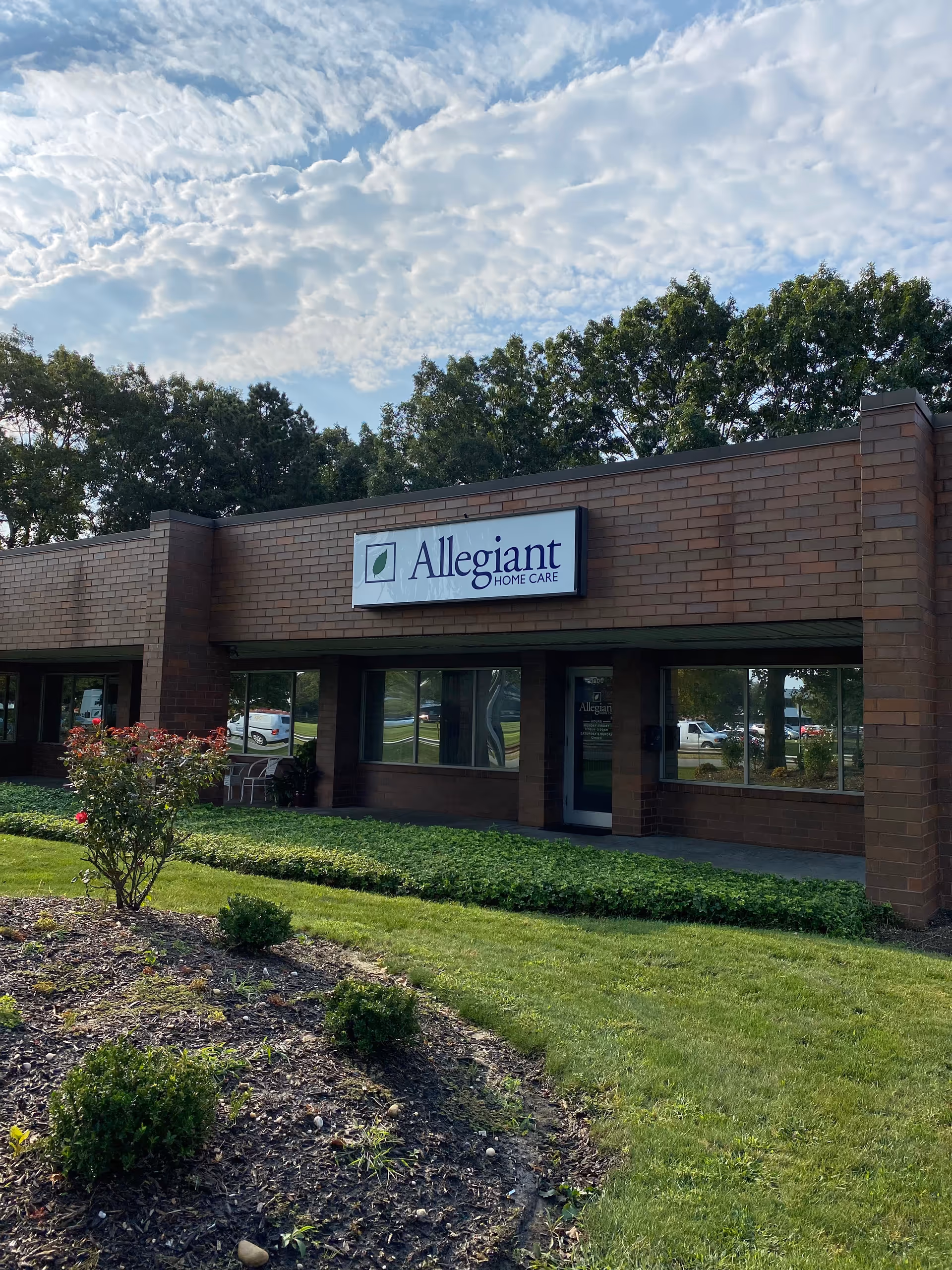 Brick exterior of Allegiant Home Care building with sign and landscaped front yard.