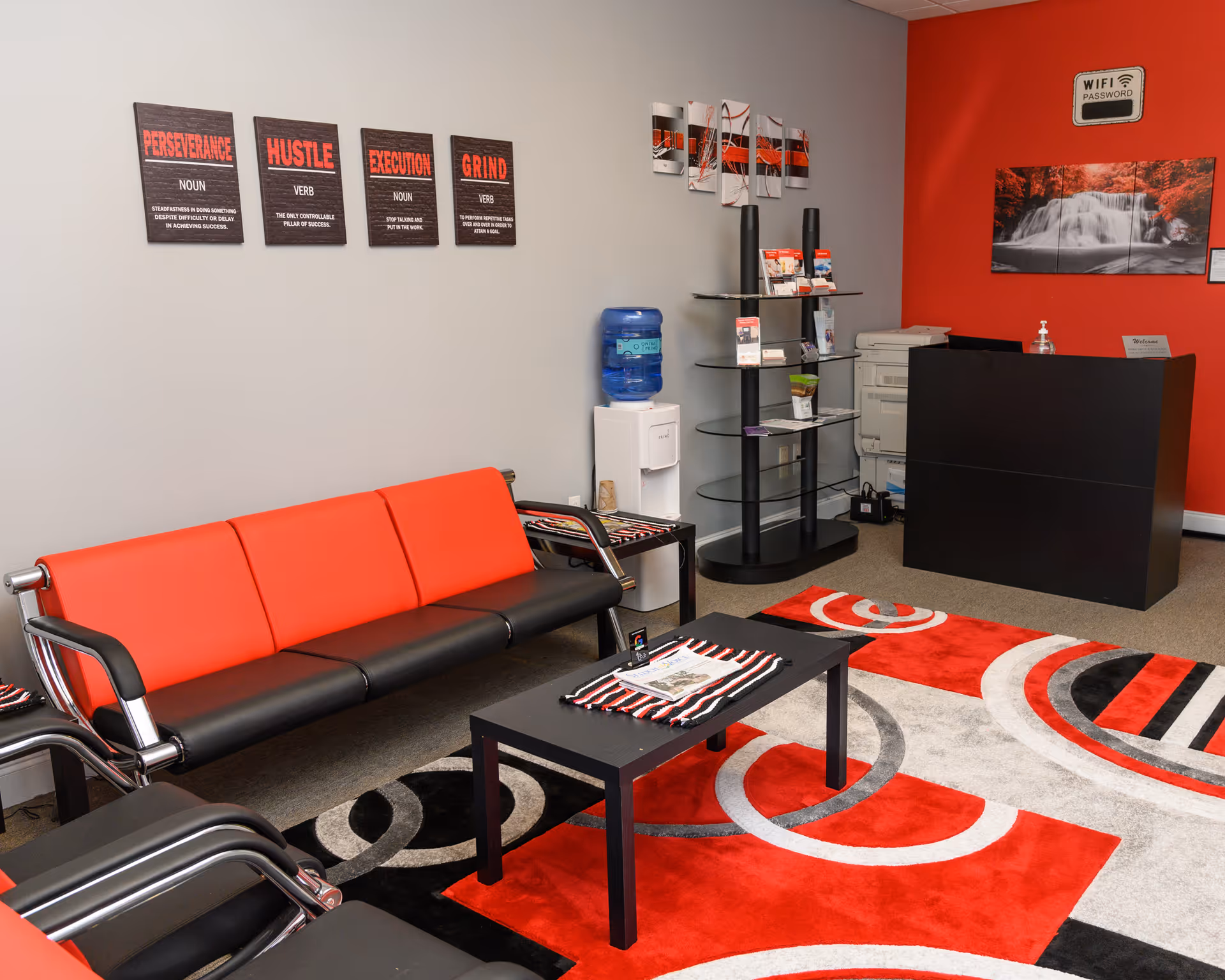 Bright reception lobby with red accents, black desk, and modern seating in an adult care facility.