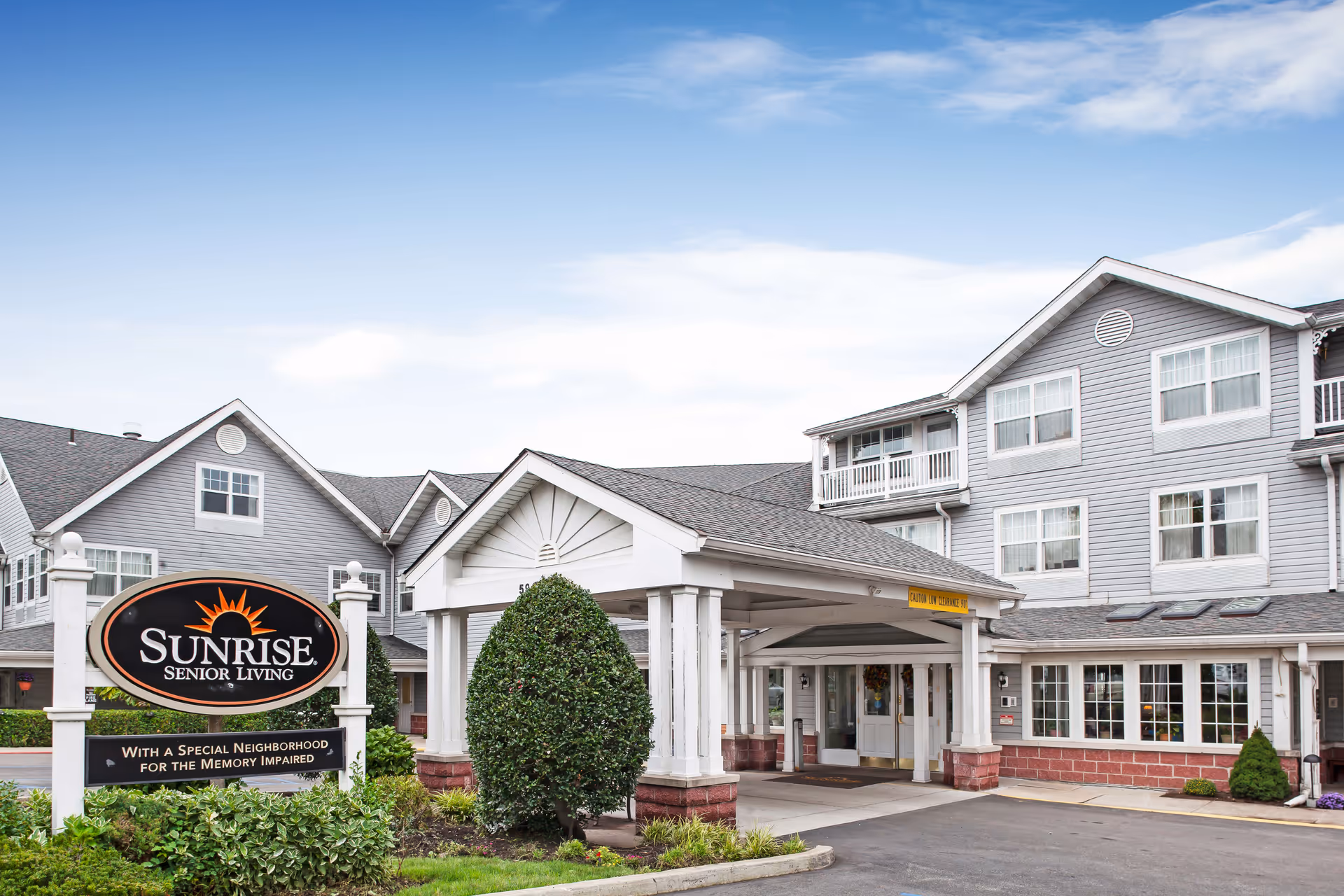 Exterior view of Sunrise Senior Living facility with entrance canopy and sign.