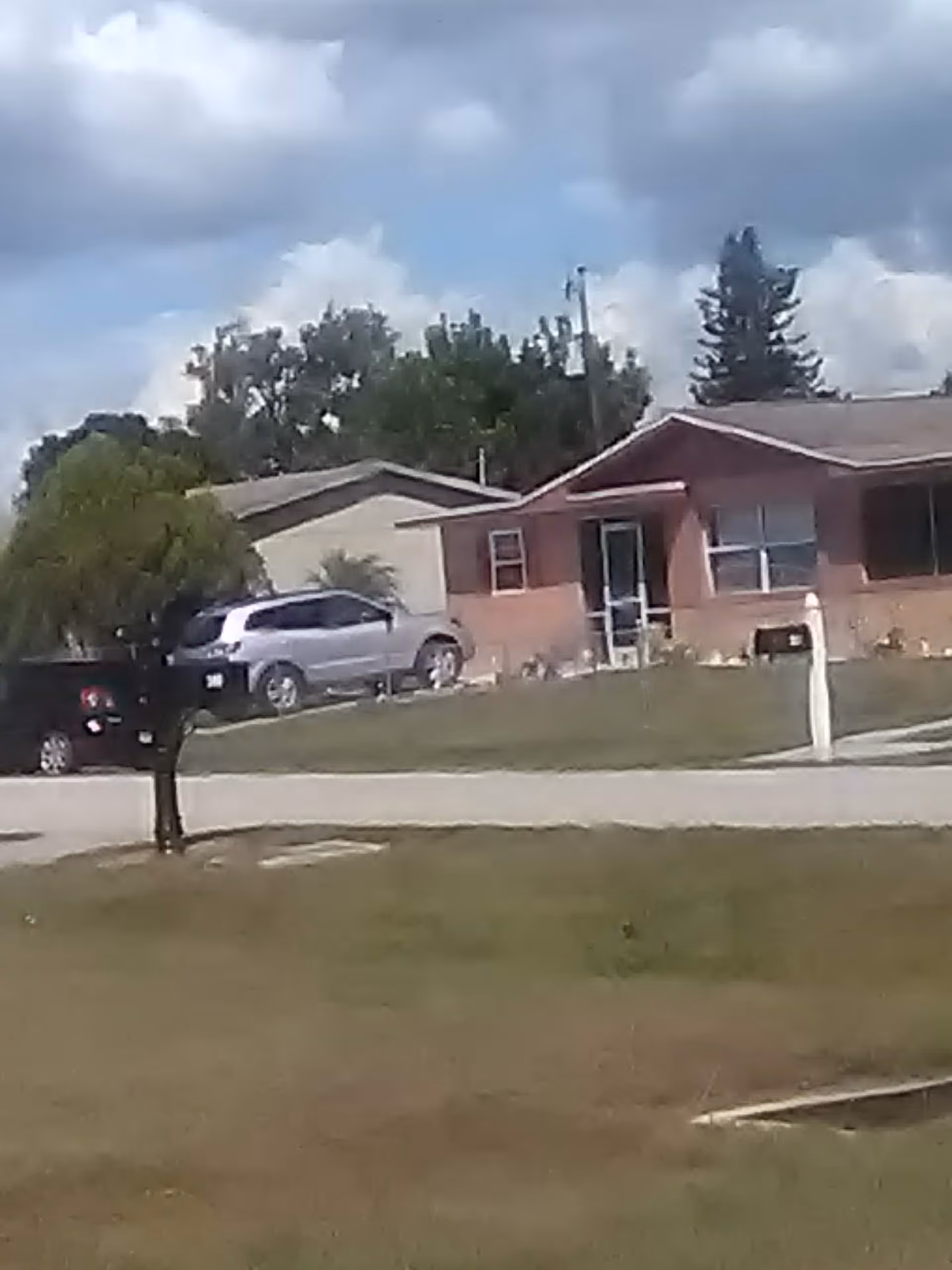 Single-story brick home with cars parked in driveway and a front yard.