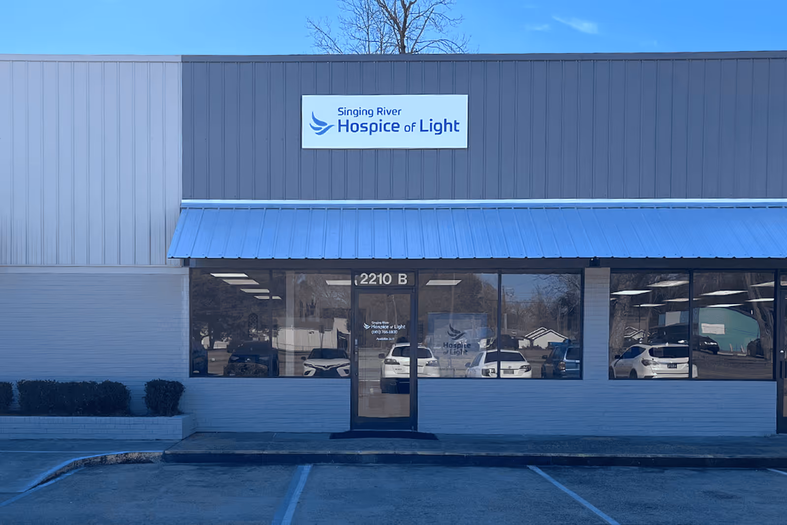 Exterior view of Singing River Hospice of Light storefront with blue awning and signage.