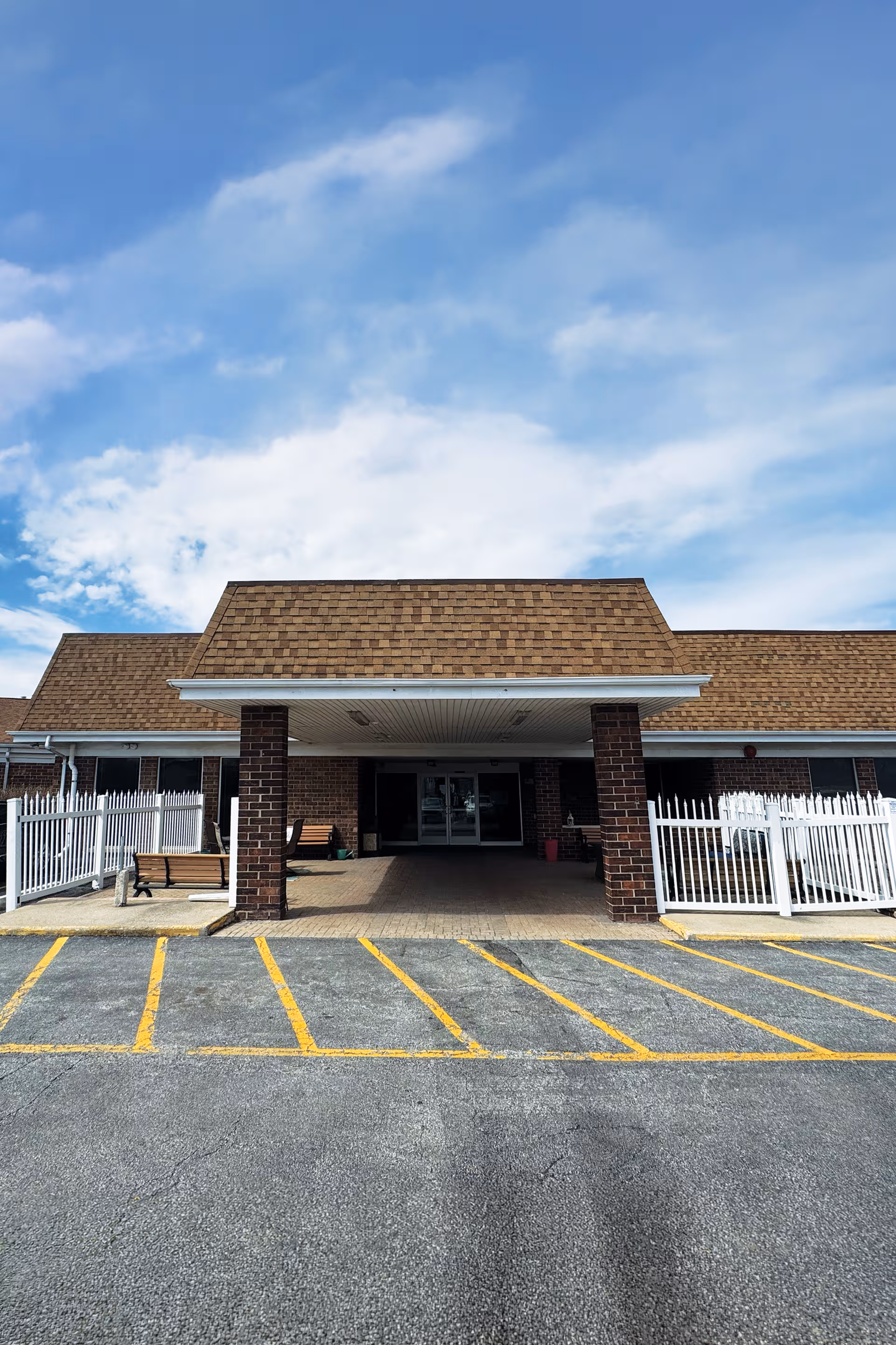 Front view of Aliya of Glenwood facility with a covered entrance and yellow-lined parking.