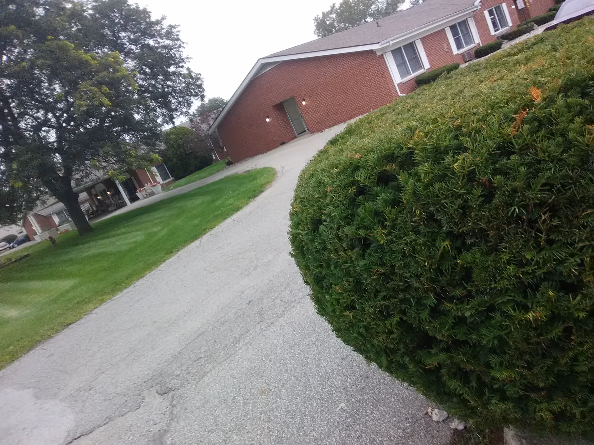 Exterior view of a brick senior living facility with driveway and lawn.