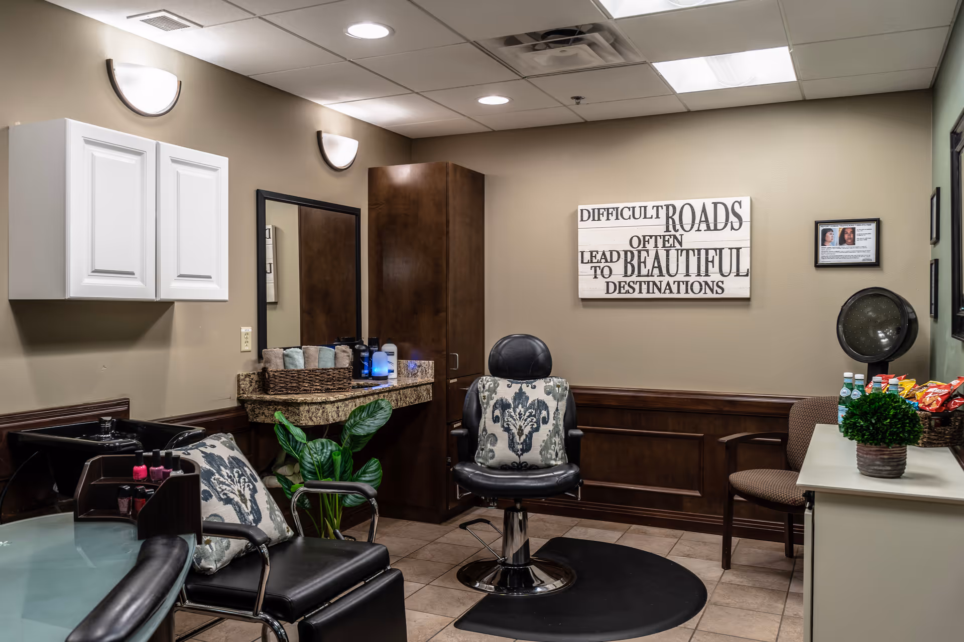 Salon area inside a senior facility with chairs, cabinets, a mirror, granite countertop, and snacks.