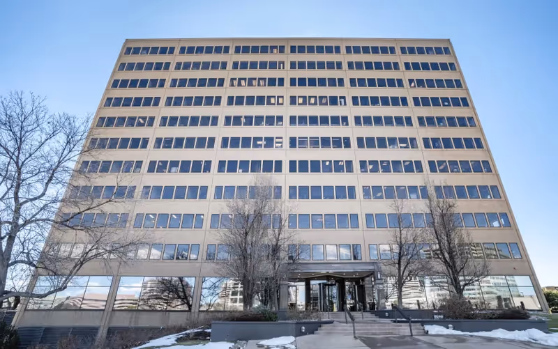 Tall beige multi-story building with many windows and a central entrance.