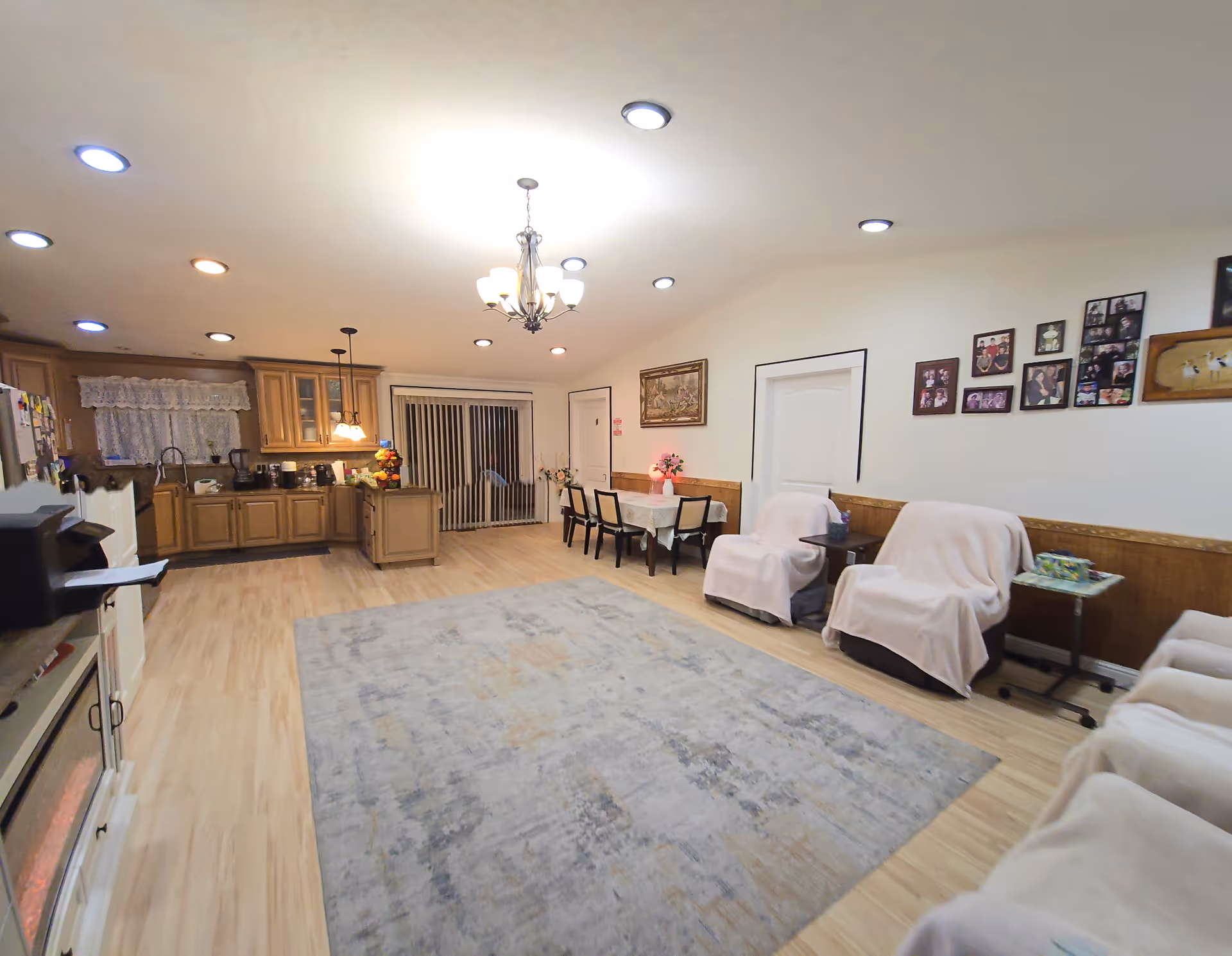 Open senior living common area featuring a kitchen, dining table, and covered chairs.