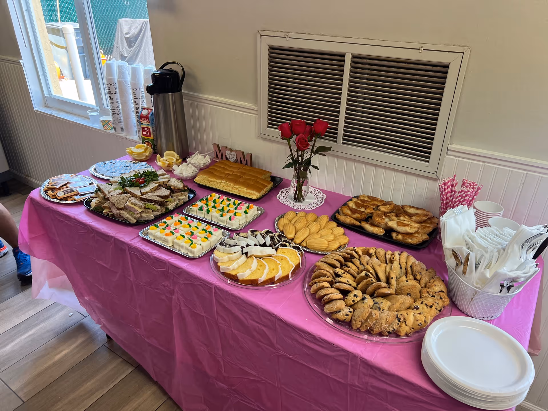 A pink tablecloth buffet table with assorted pastries indoors.