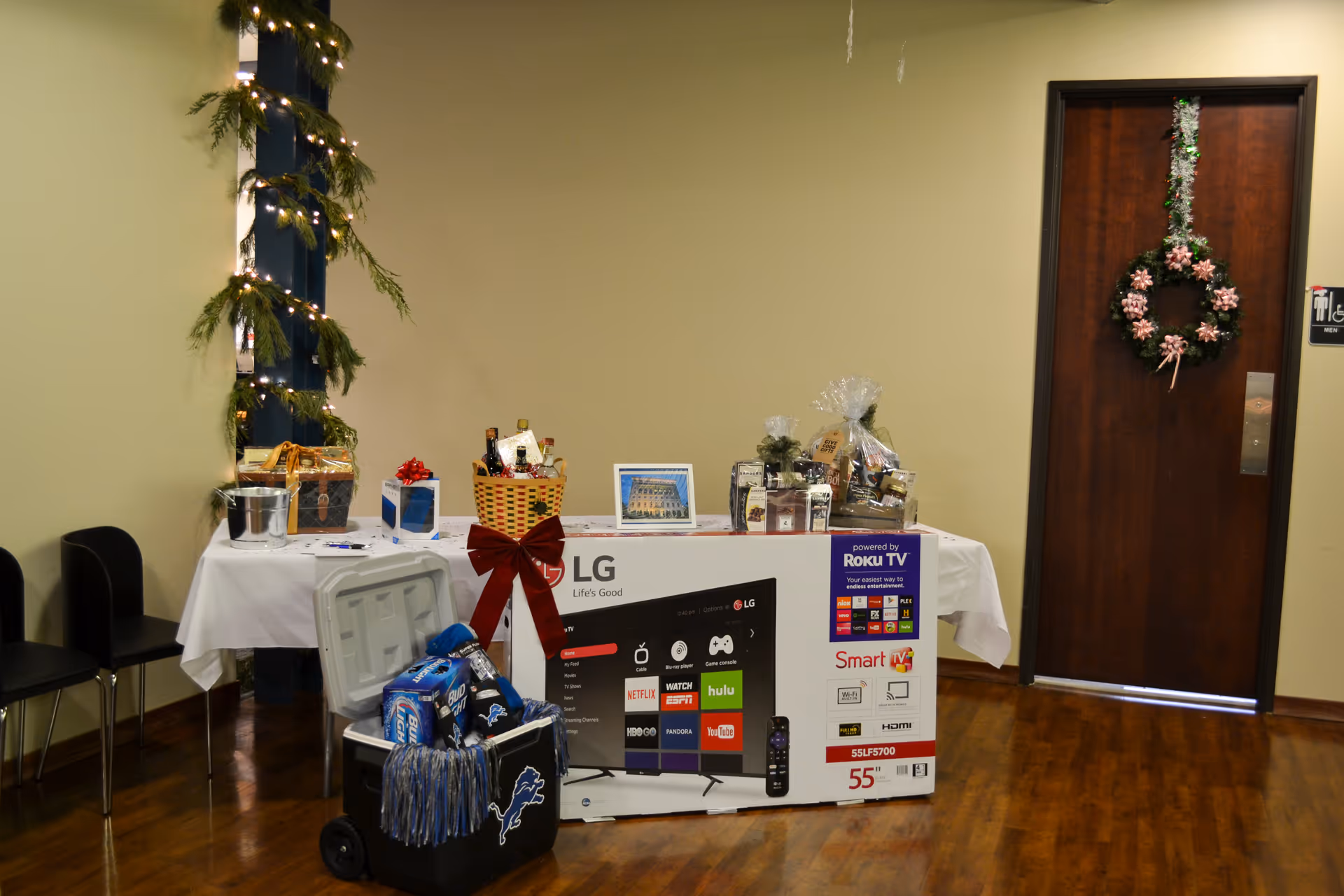 Indoor event setup with a prize table, gifts, and a large LG TV box.