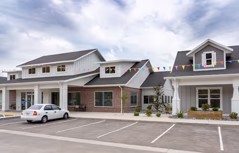 Exterior view of Petersen Farms Assisted Living with a parking lot and festive bunting.