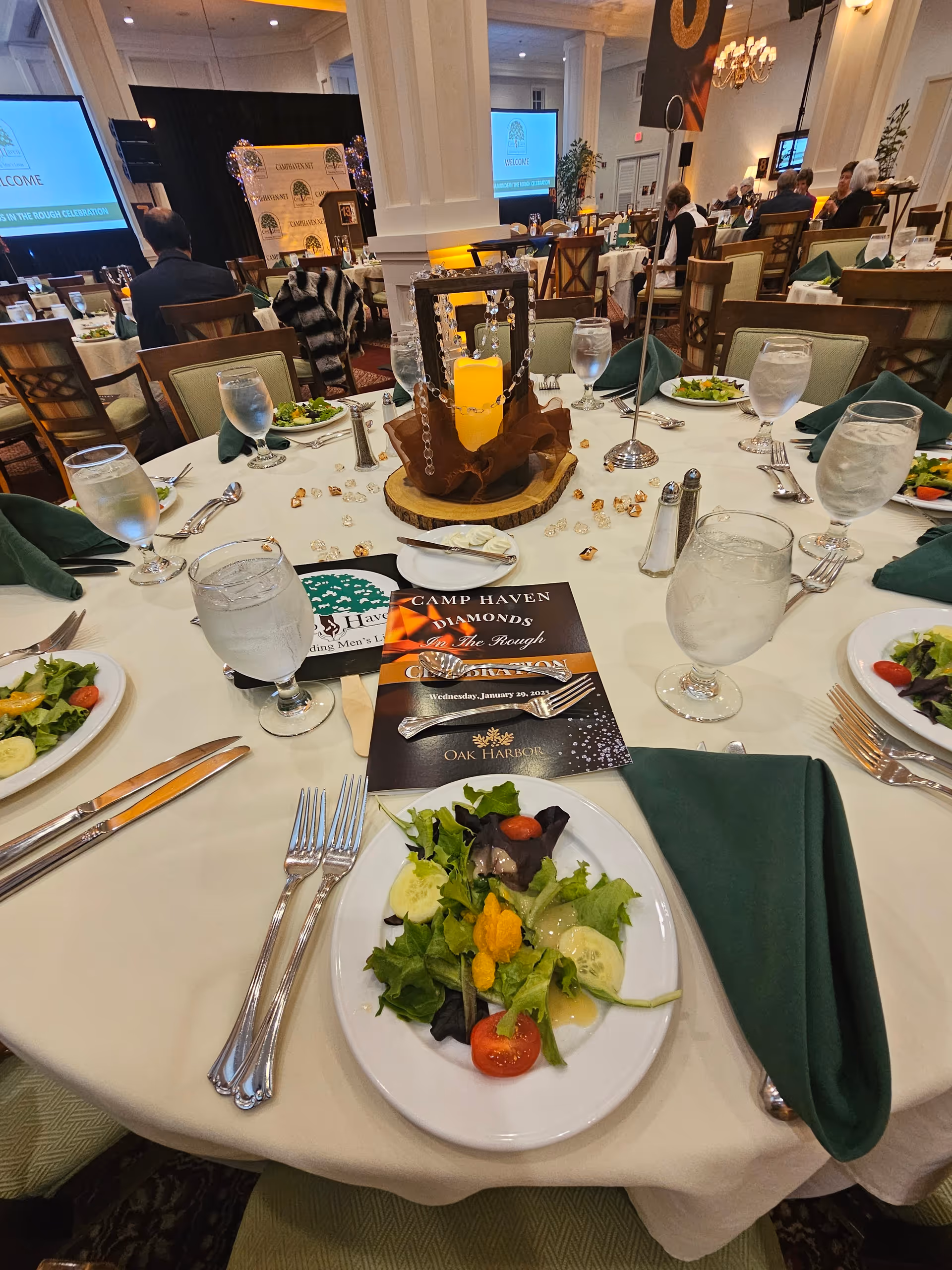 Formal dining setup with round tables, place settings, and centerpieces in a large hall.