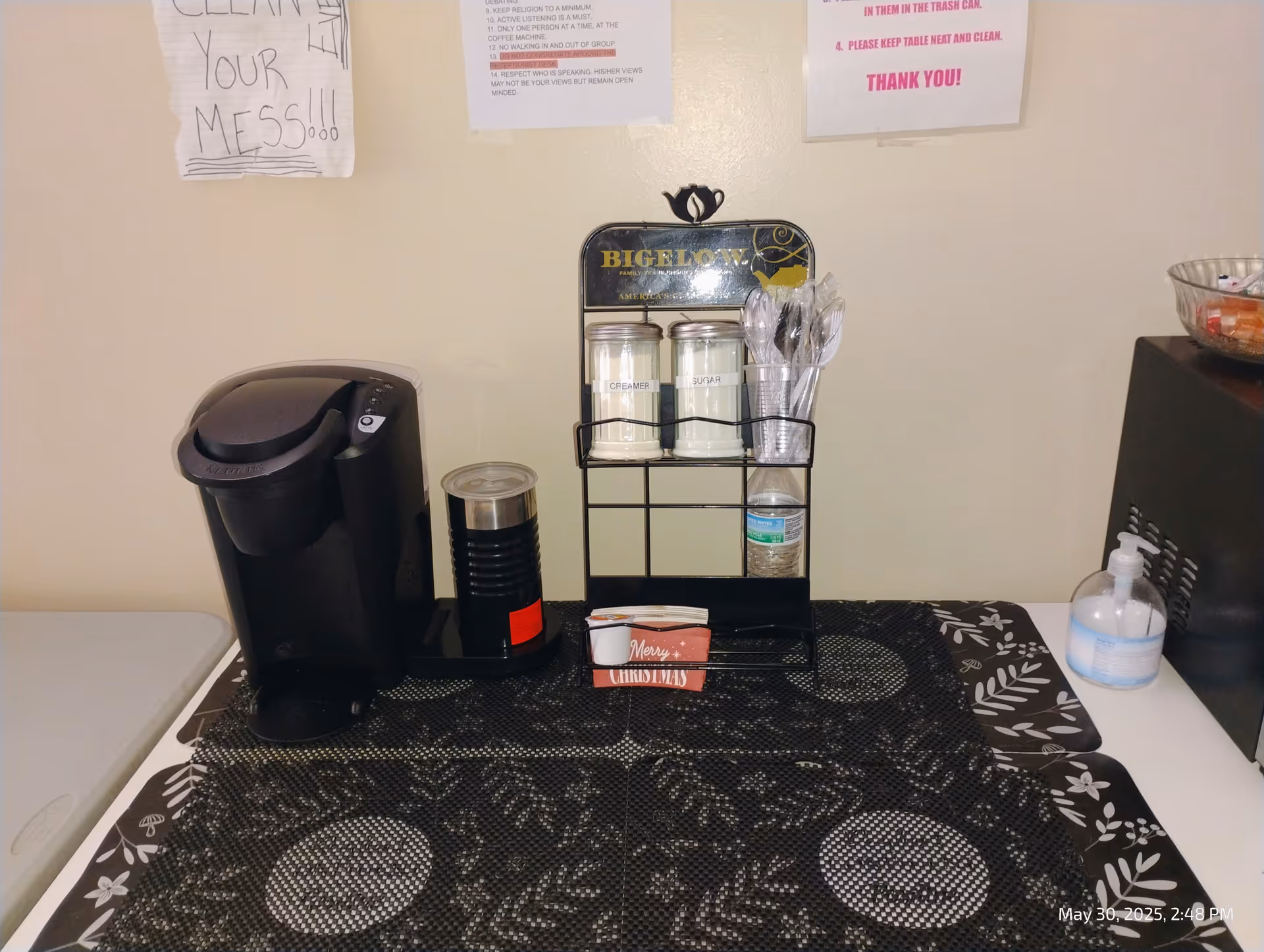 Coffee station with a Keurig, sugar jars, utensils on a patterned counter.