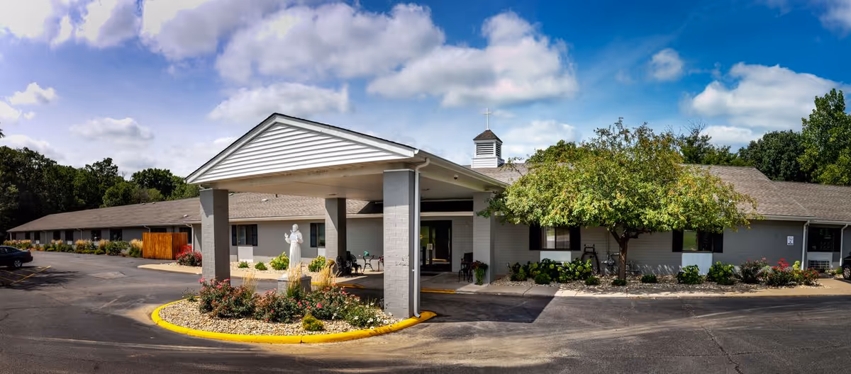 Exterior view of St. Francis Woods senior living facility with a porte-cochère entry and manicured landscaping.