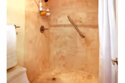 A tiled bathroom shower area with a grab bar and white shower curtain.