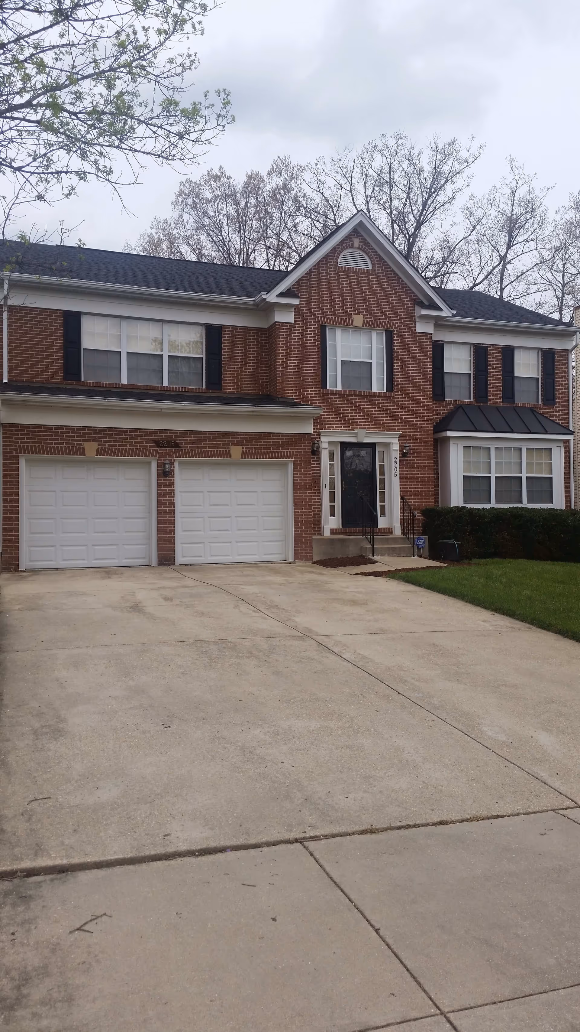 Two-story brick building with a double garage and concrete driveway.