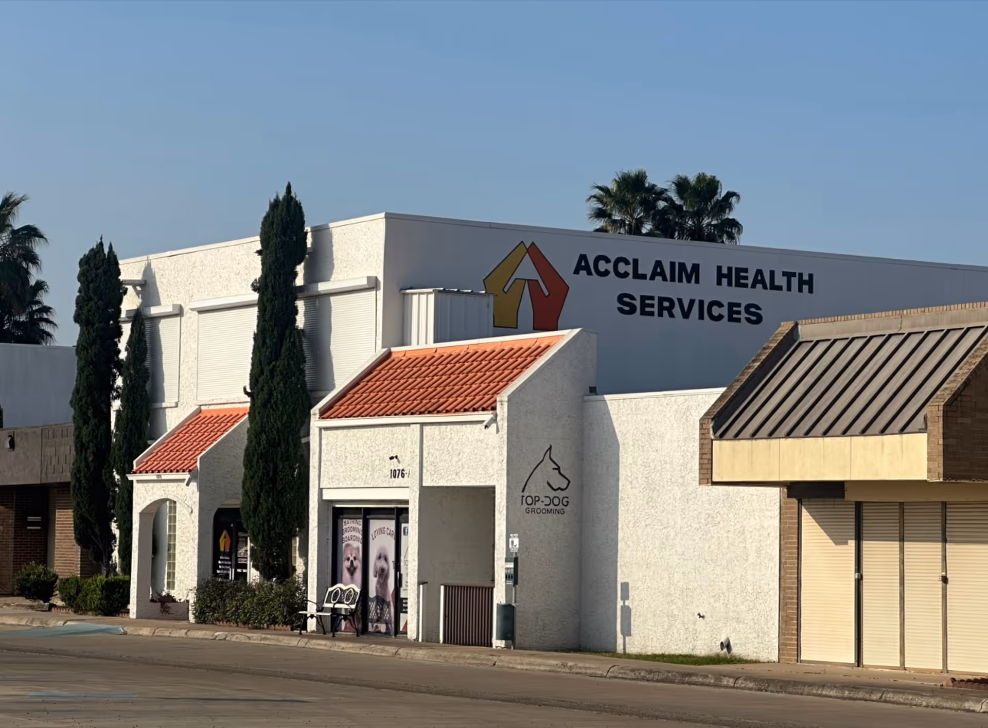 Exterior view of Acclaim Health Services building with white walls and tall trees.