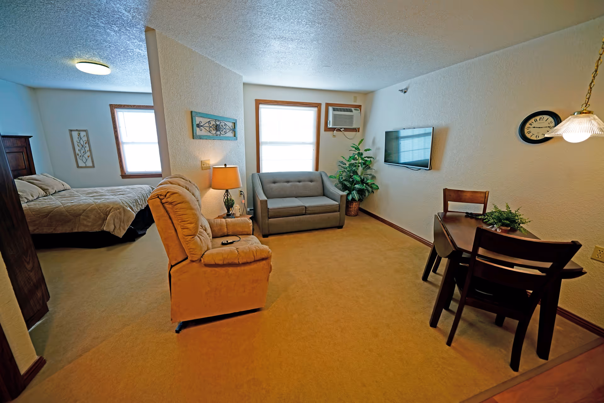 Cozy living area with sofa, recliner, dining table, and a bed.