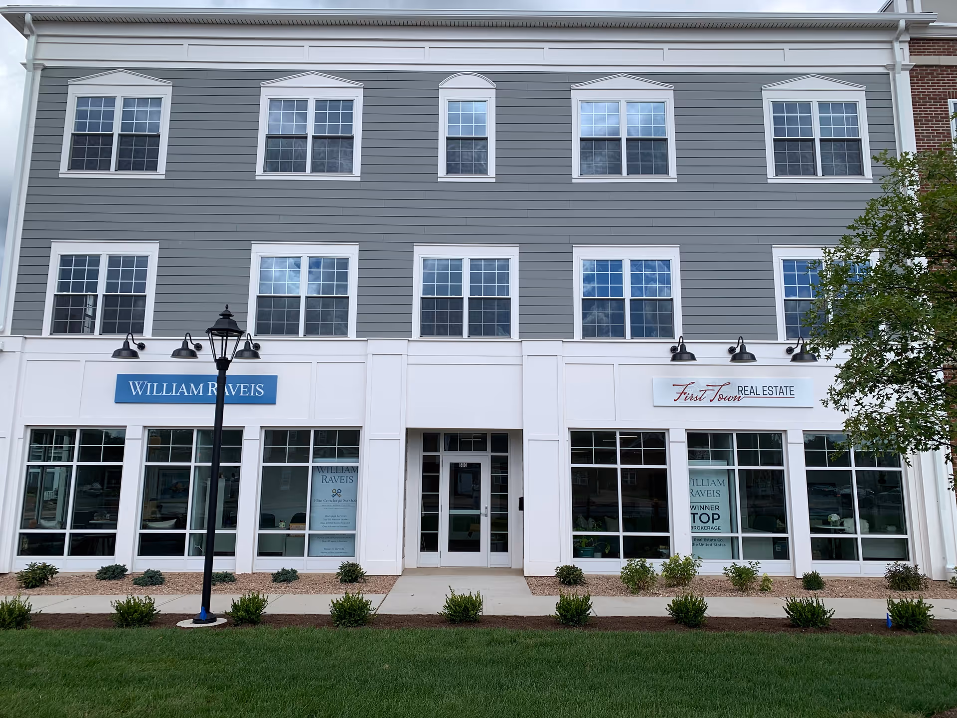 Two-story building facade with multiple storefronts and real estate signs.