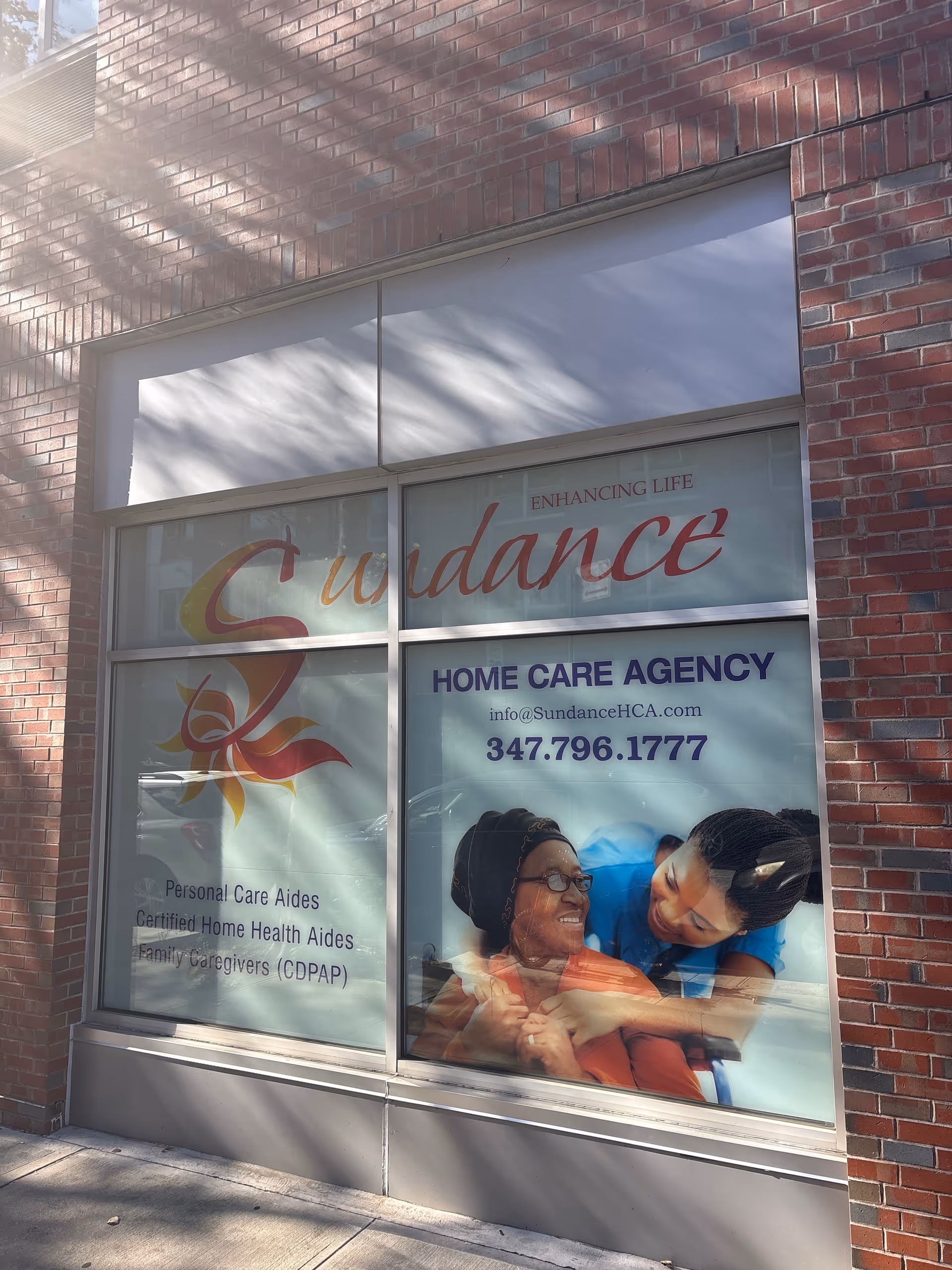 Brick storefront with Sundance Home Care Agency branding on large glass windows.