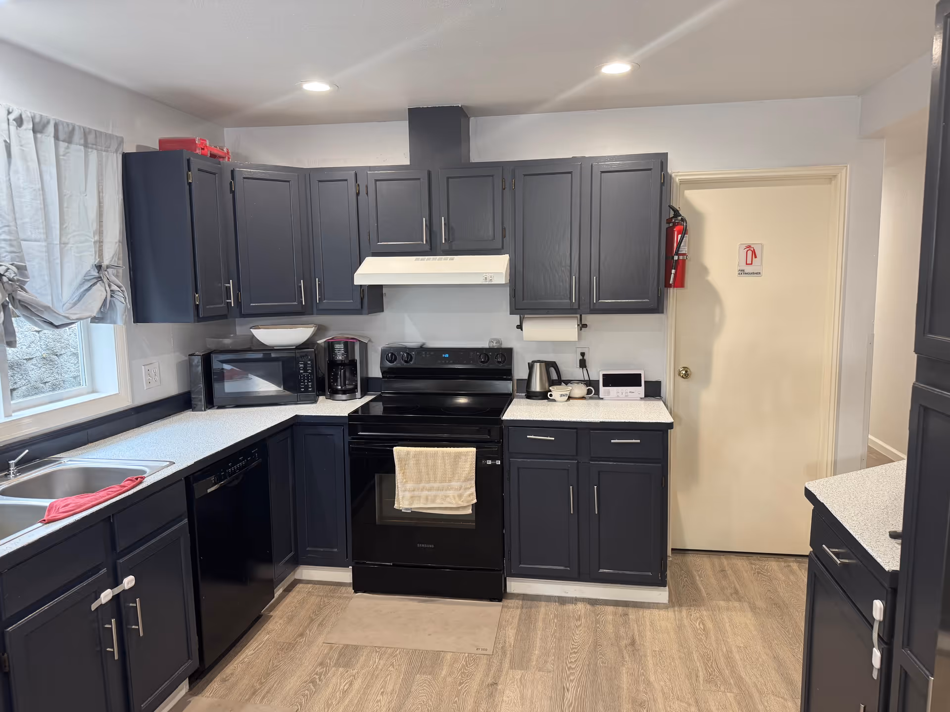 Dark blue cabinets surround a U-shaped kitchen with stove, sink, and appliances.