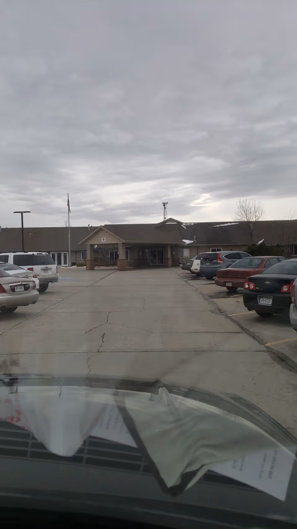 Front exterior of Prairie Pines Lodge with a parking lot and parked cars