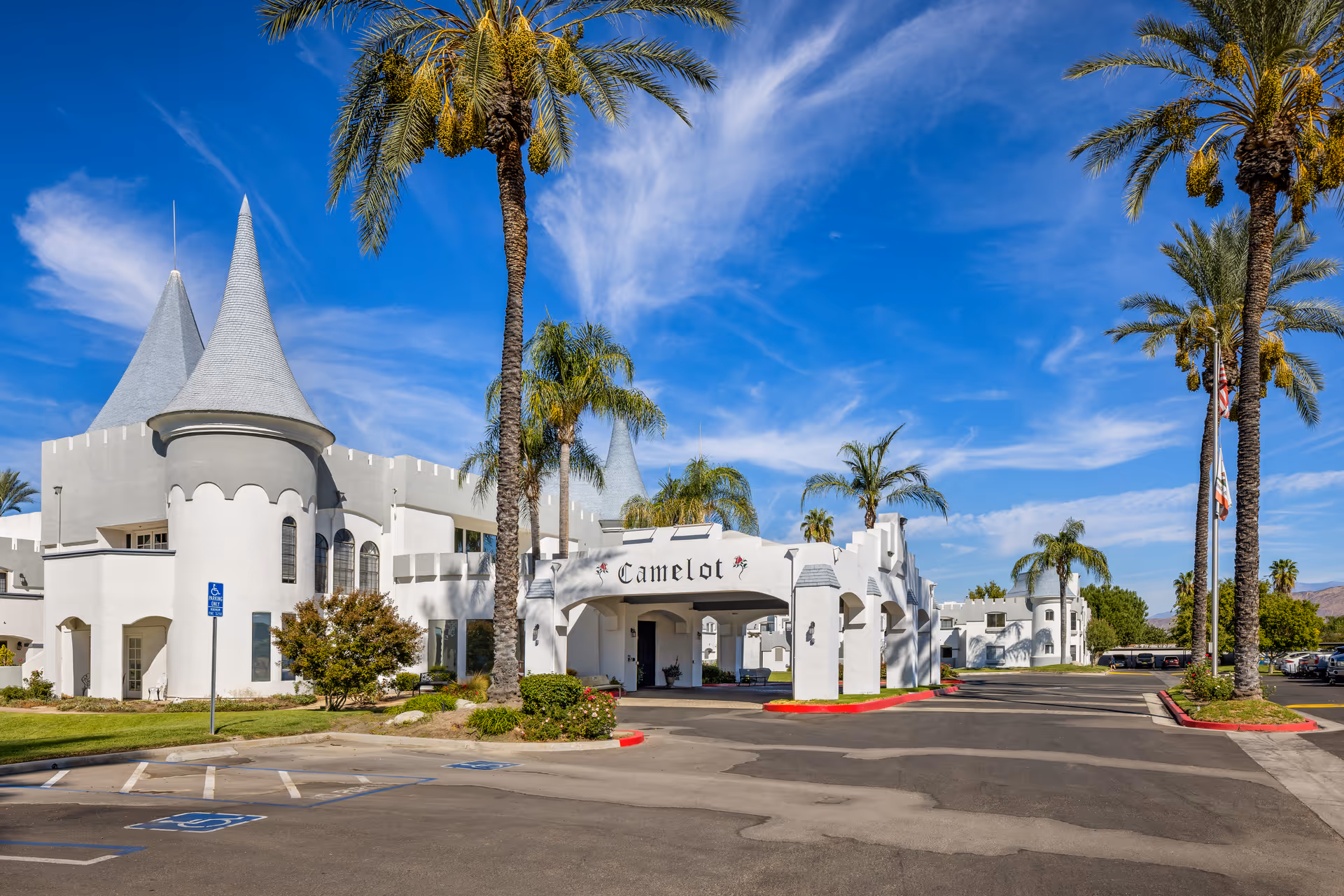 White castle-style senior living facility with palm trees and a blue sky.