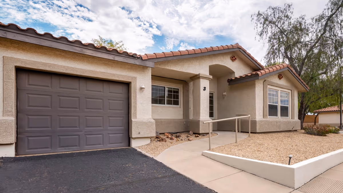 Single-story senior living facility with beige exterior, arched entry, and ramp.