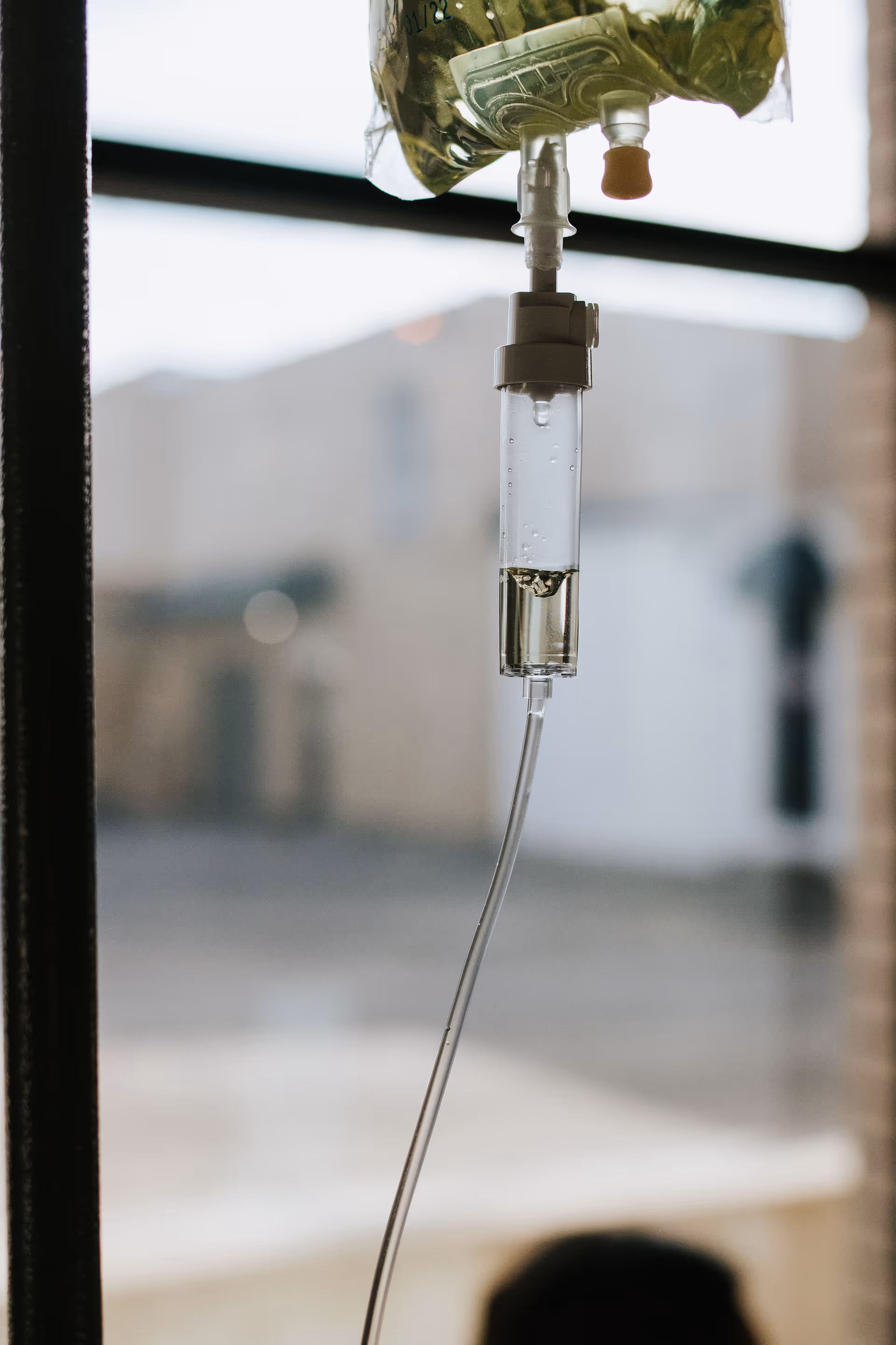 Close-up of an IV bag and tubing in a clinical setting.