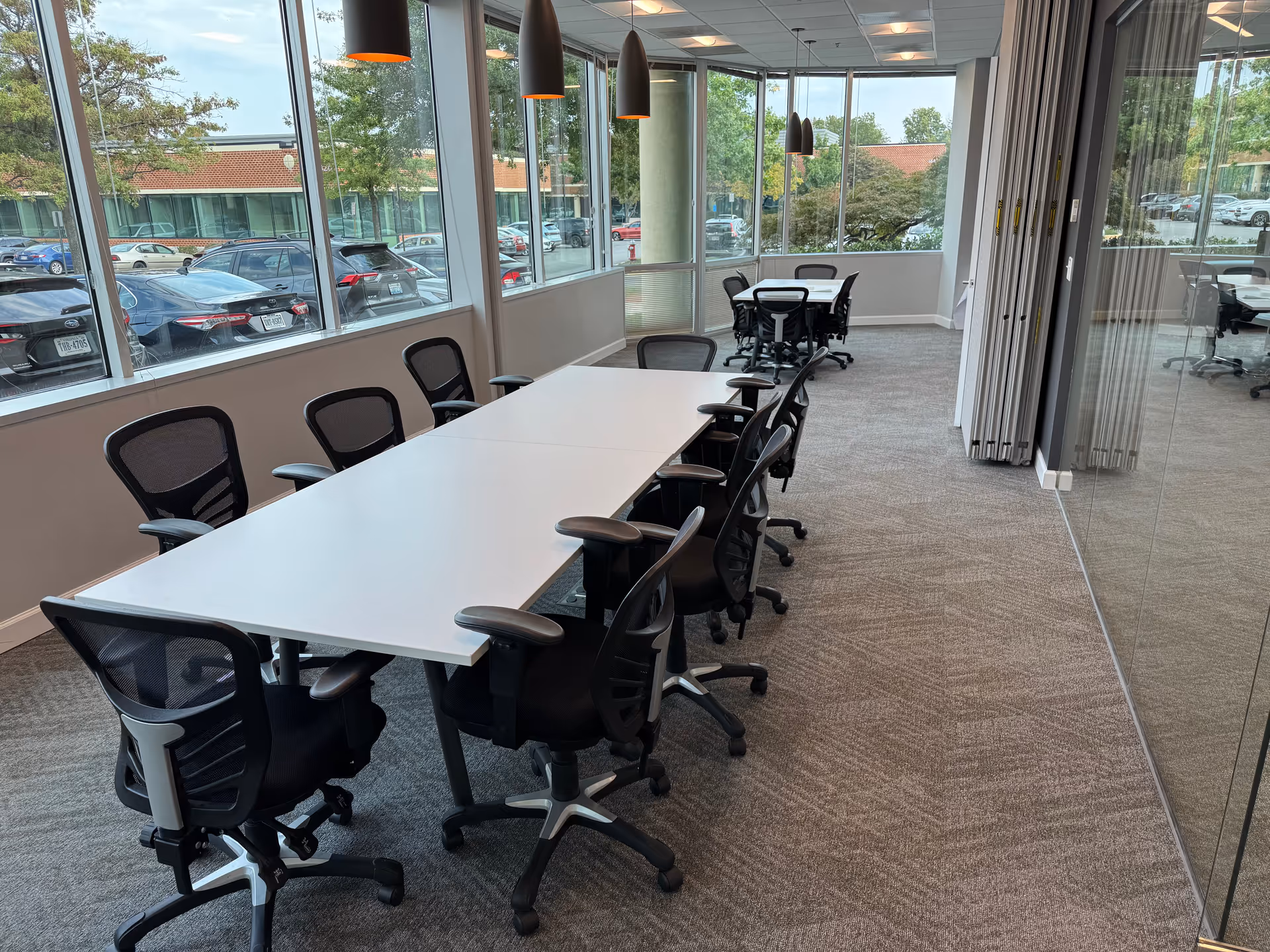 Bright conference room with a long white table and multiple black ergonomic chairs.