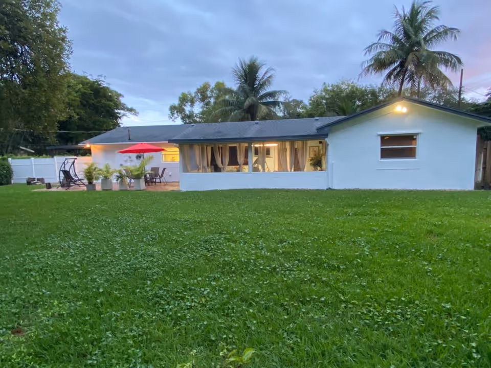 White, single-story senior care home with large windows, green lawn, and outdoor seating.