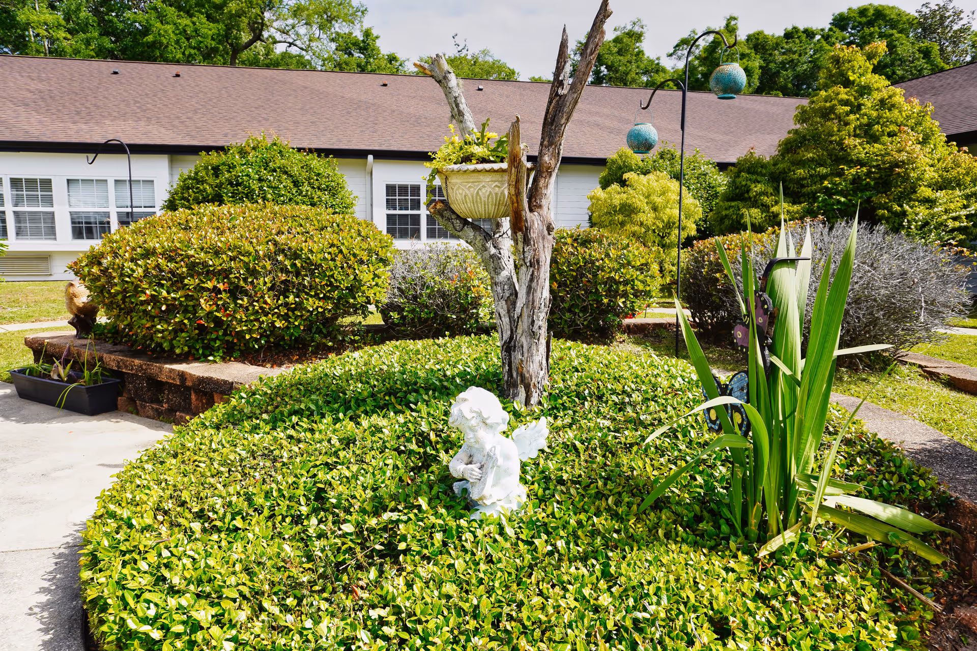 Well-manicured hedges enclose a small statue in a garden in front of a building.