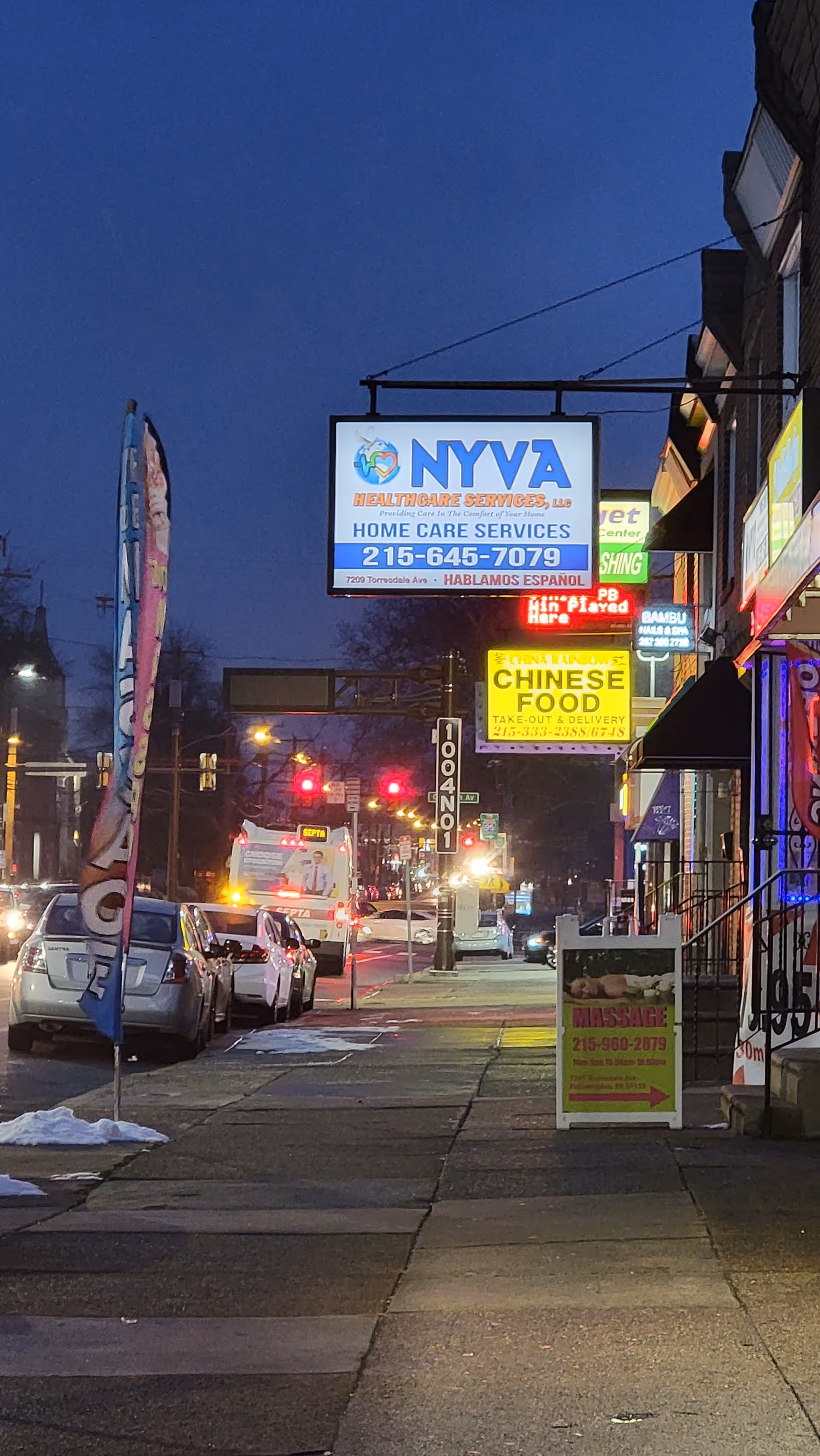 Nighttime street view with NYVA Healthcare Services sign and storefronts