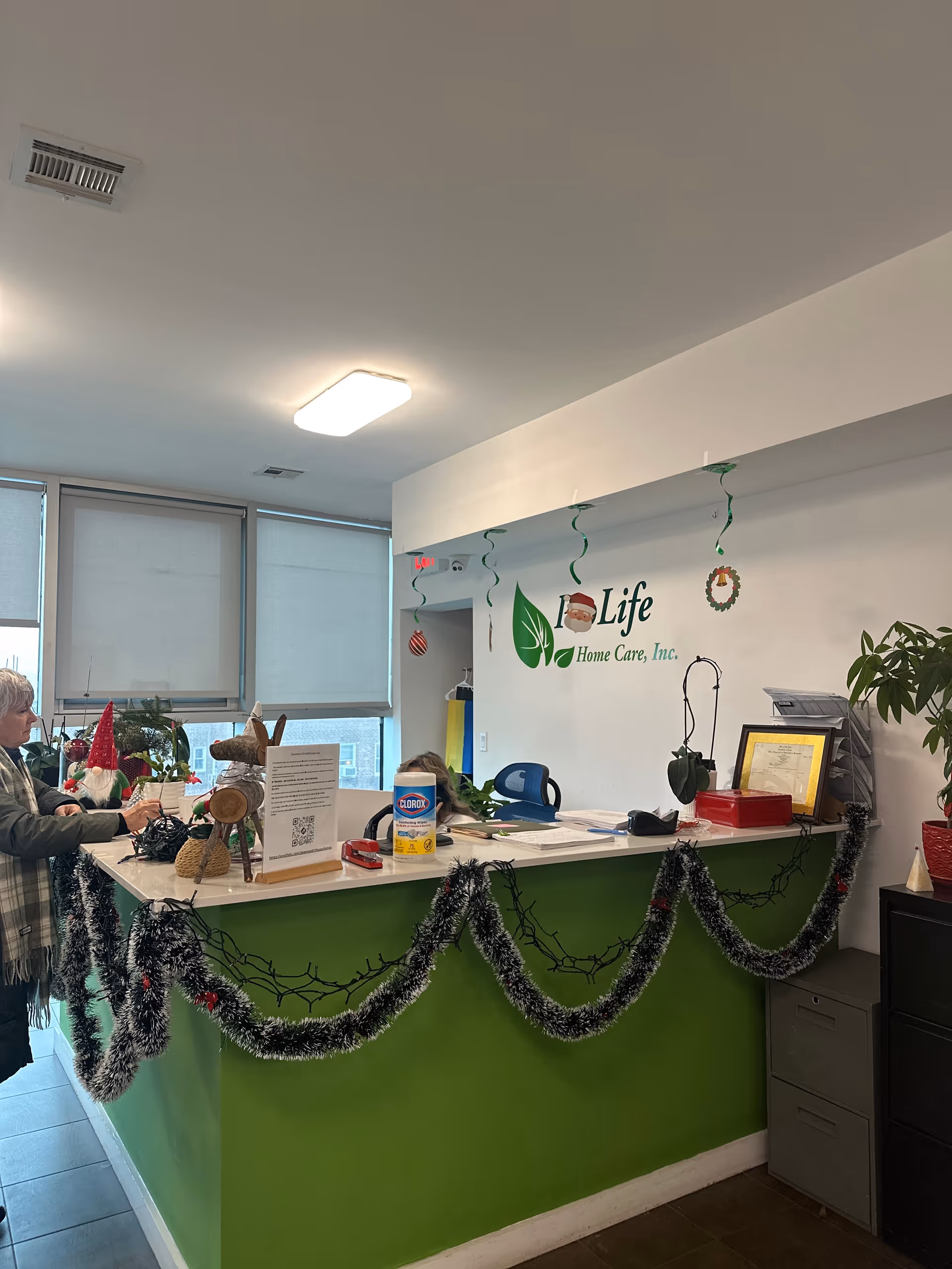 Reception desk inside a bright lobby with green counter and holiday garlands