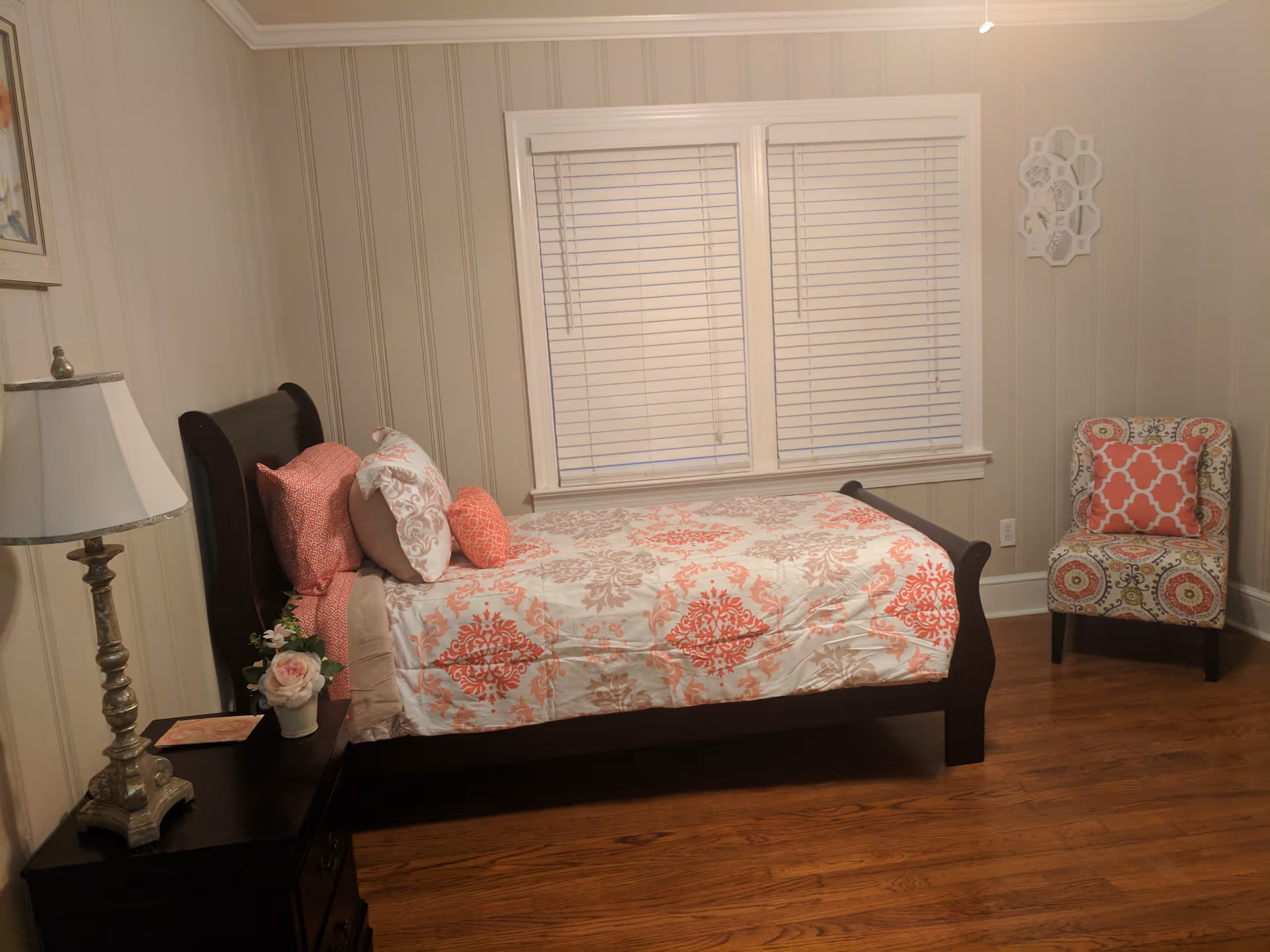Cozy bedroom featuring a patterned bed, lamp, nightstand, and decorative chair.