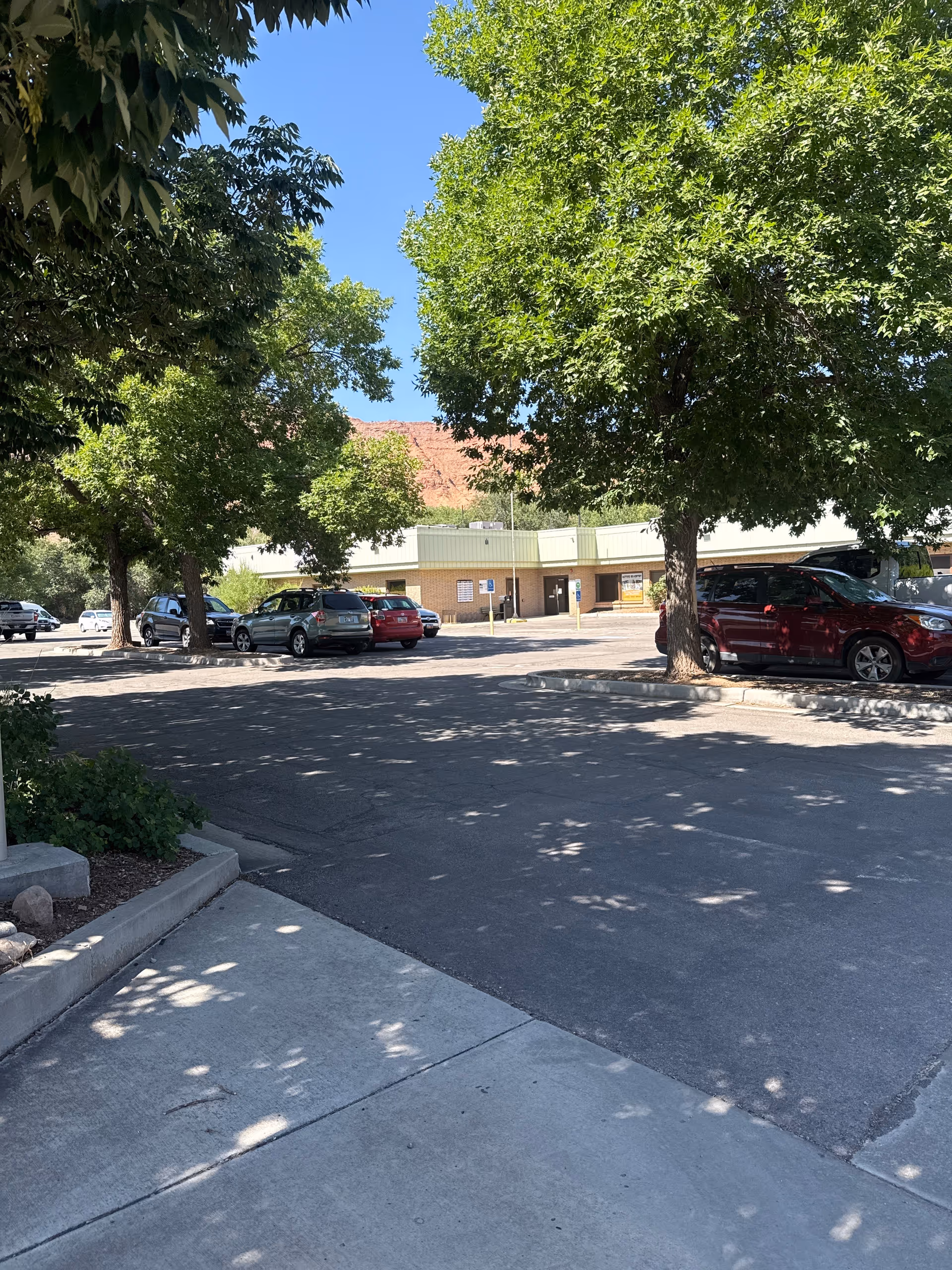 Exterior view of a senior living facility with a parking lot and trees.