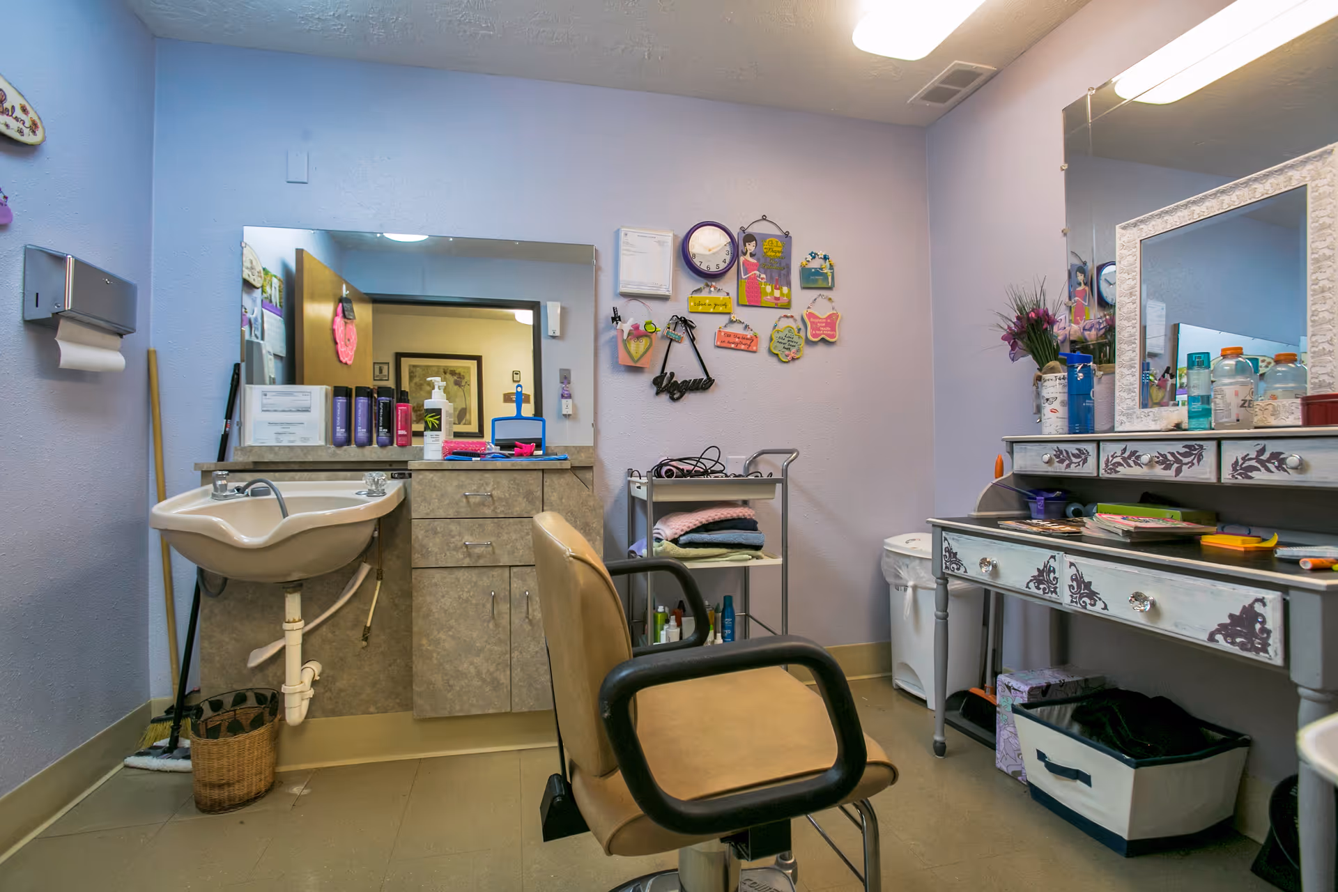 Interior grooming station in a nursing facility with sink, mirror, chair, and vanity.