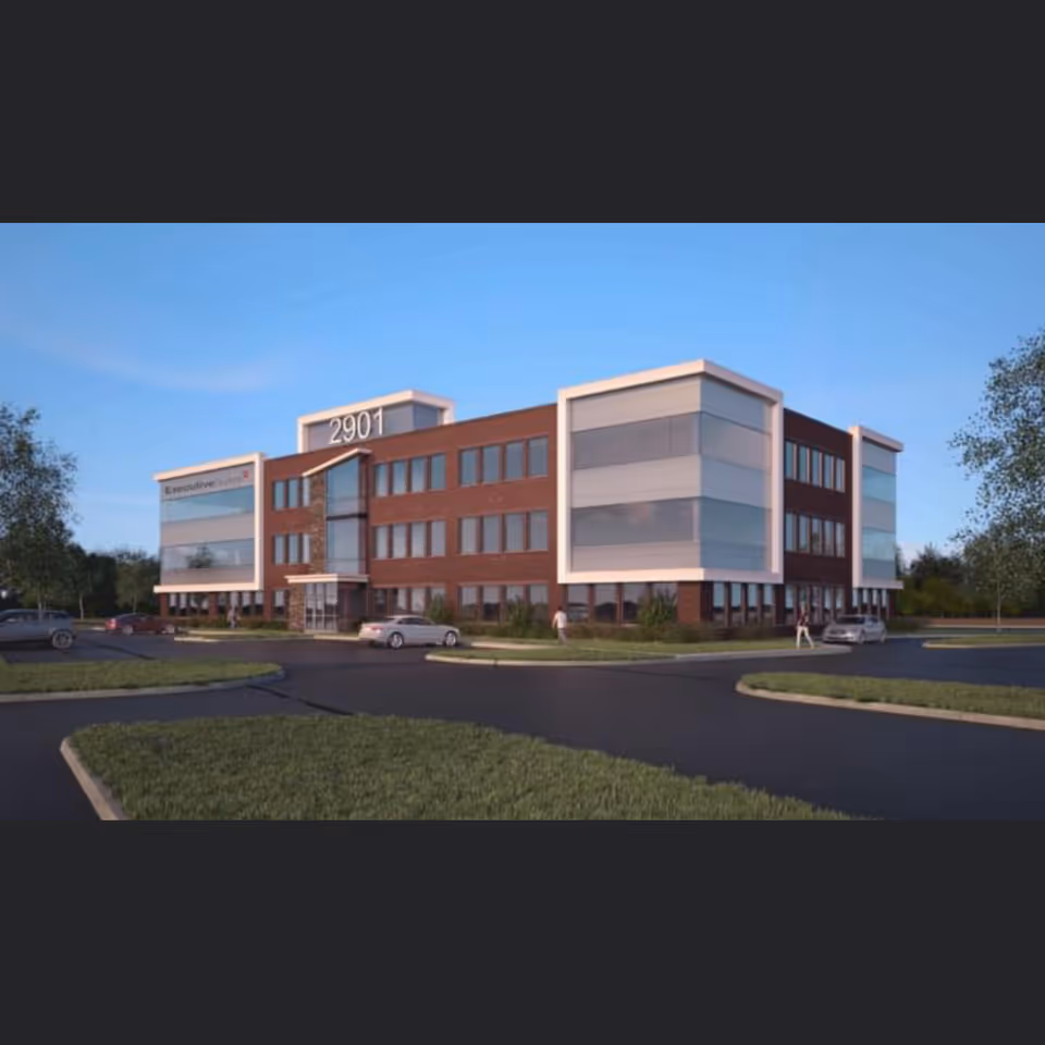 Exterior view of a modern Aspire Concierge Care building with brick, glass facade and surrounding parking.