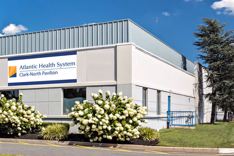 Exterior view of Atlantic Health System Clark-North Pavilion with manicured shrubs and sign.
