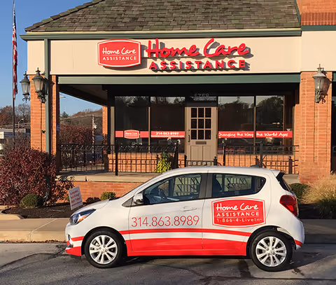 Exterior view of Home Care Assistance storefront with branded car parked in front.