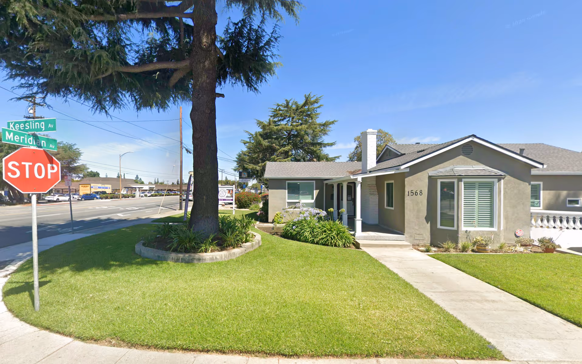 Front view of a single-story beige senior living facility with a manicured lawn.