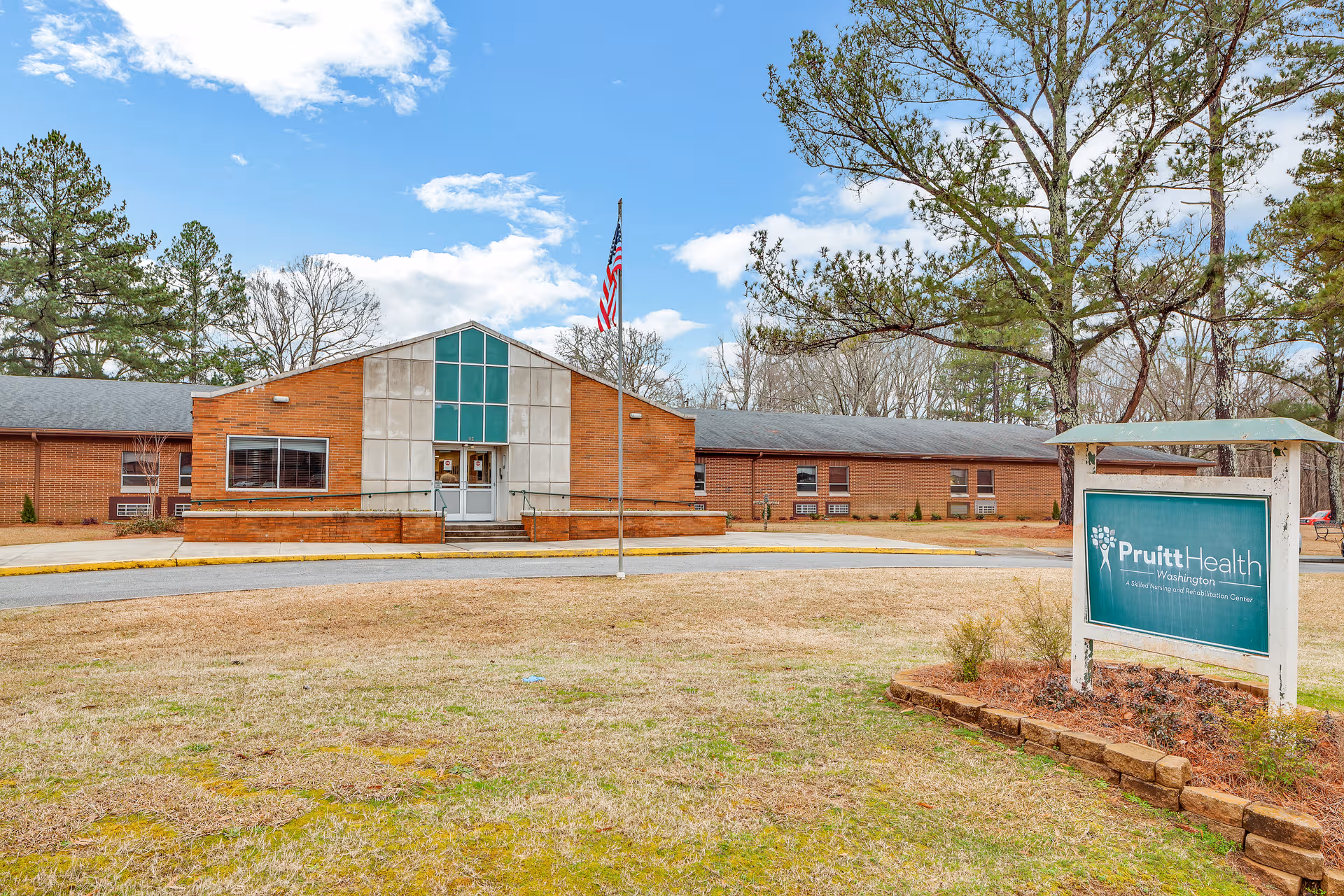 Brick senior living facility with flagpole, front entrance, and a PruittHealth sign.